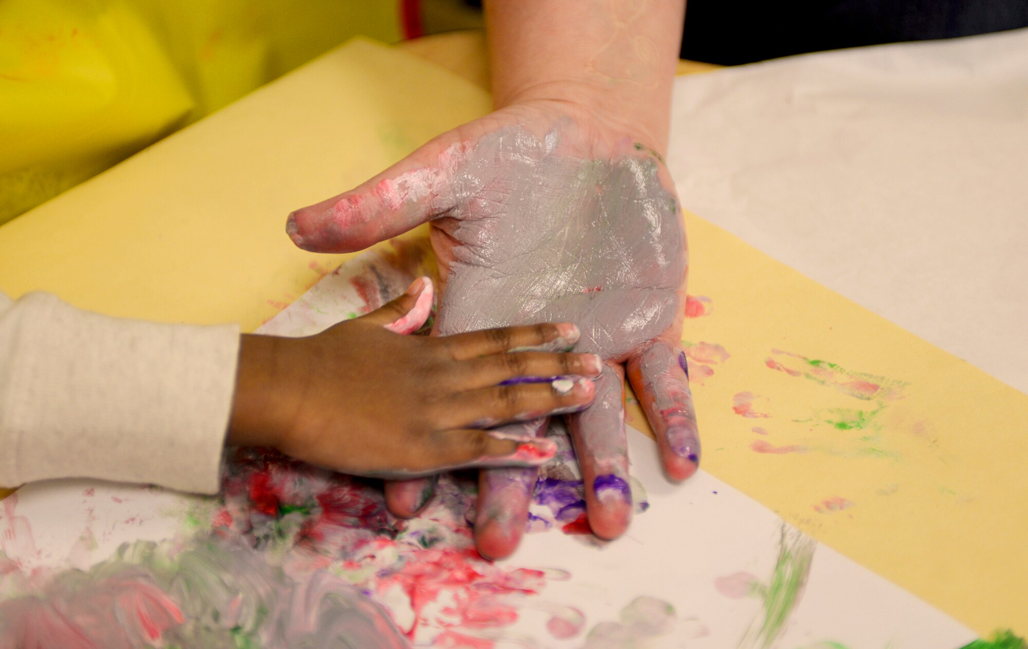 A Child Development Center II student and caregiver, paint together during Winter Wonderland Dec. 12, 2014, at Moody Air Force Base, Ga. The children used frozen finger paint that melts on contact to keep with the winter theme. (U.S. Air Force photo by Senior Airman Sandra Marrero/Released)
