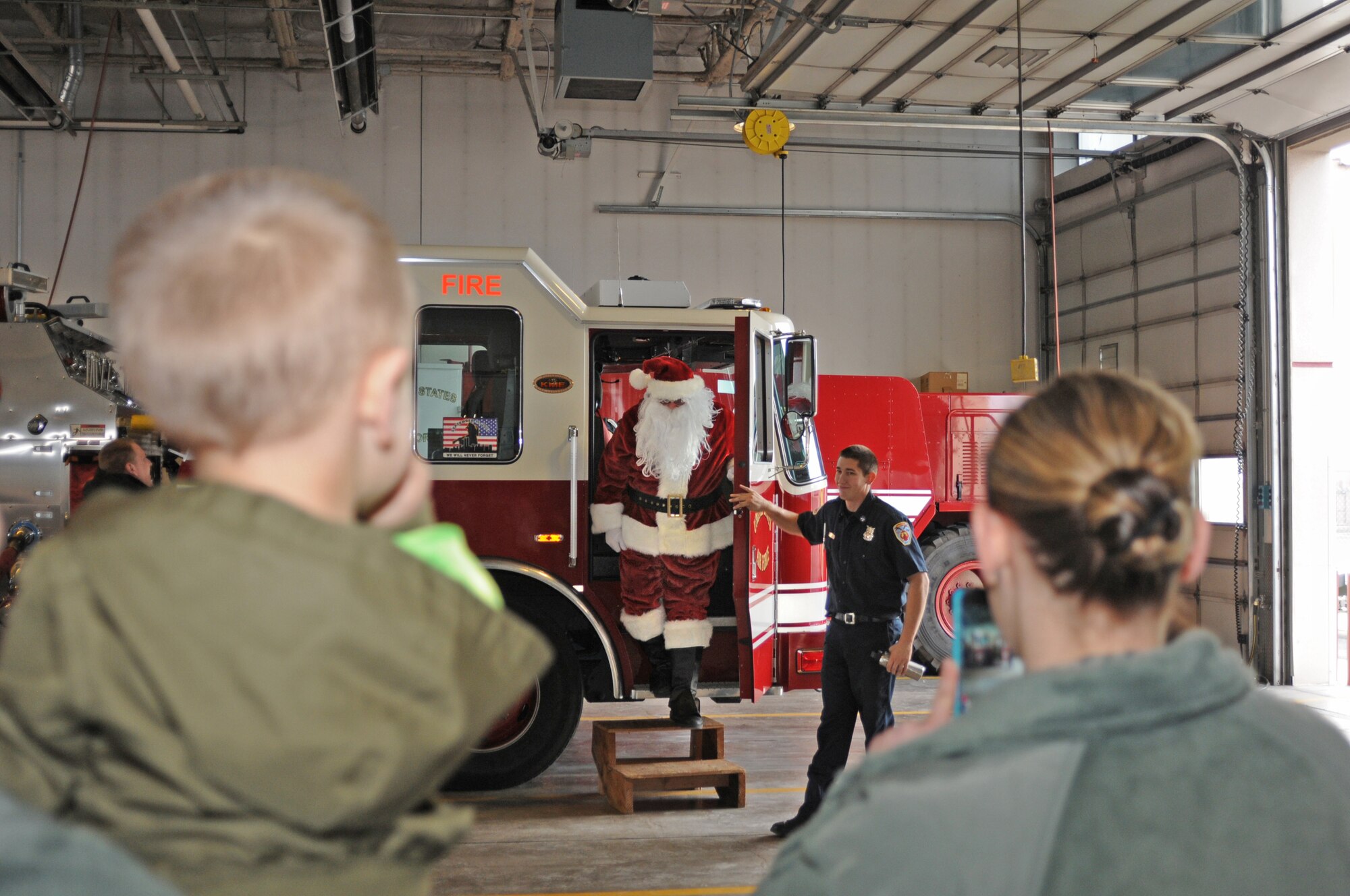 Excited children and their parents watch as Santa Clause arrives at the Kingsley Field fire station in fire truck Dec. 7, 2014.  Because of construction on the main hangar, the annual children's Christmas carnival had been cancelled, but thanks to a few Kingsley members they were able to organize a smaller gathering for the young children at the fire house.  (U.S. Air National Guard photo by Tech. Sgt. Daniel Condit / Released)