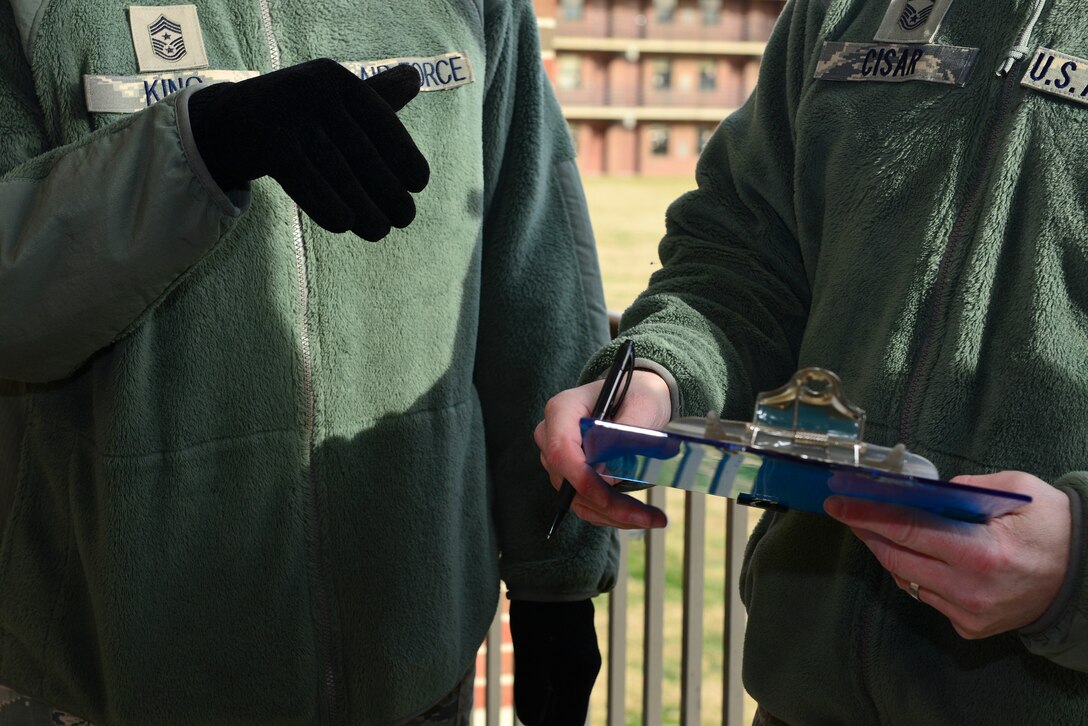 U.S. Air Force Chief Master Sgt. Trae King, 633rd Air Base Wing command chief, and Master Sgt. John Cisar, 633rd Civil Engineer Squadron Unaccompanied Housing superintendent, go over their notes during the judging of the Dorm Door Decorating Contest at Langley Air Force Base, Va., Dec. 12, 2014. King and the Dorm Management staff looked at each door, judging as they went. (U.S. Air Force photo by Senior Airman Kimberly Nagle/Released)