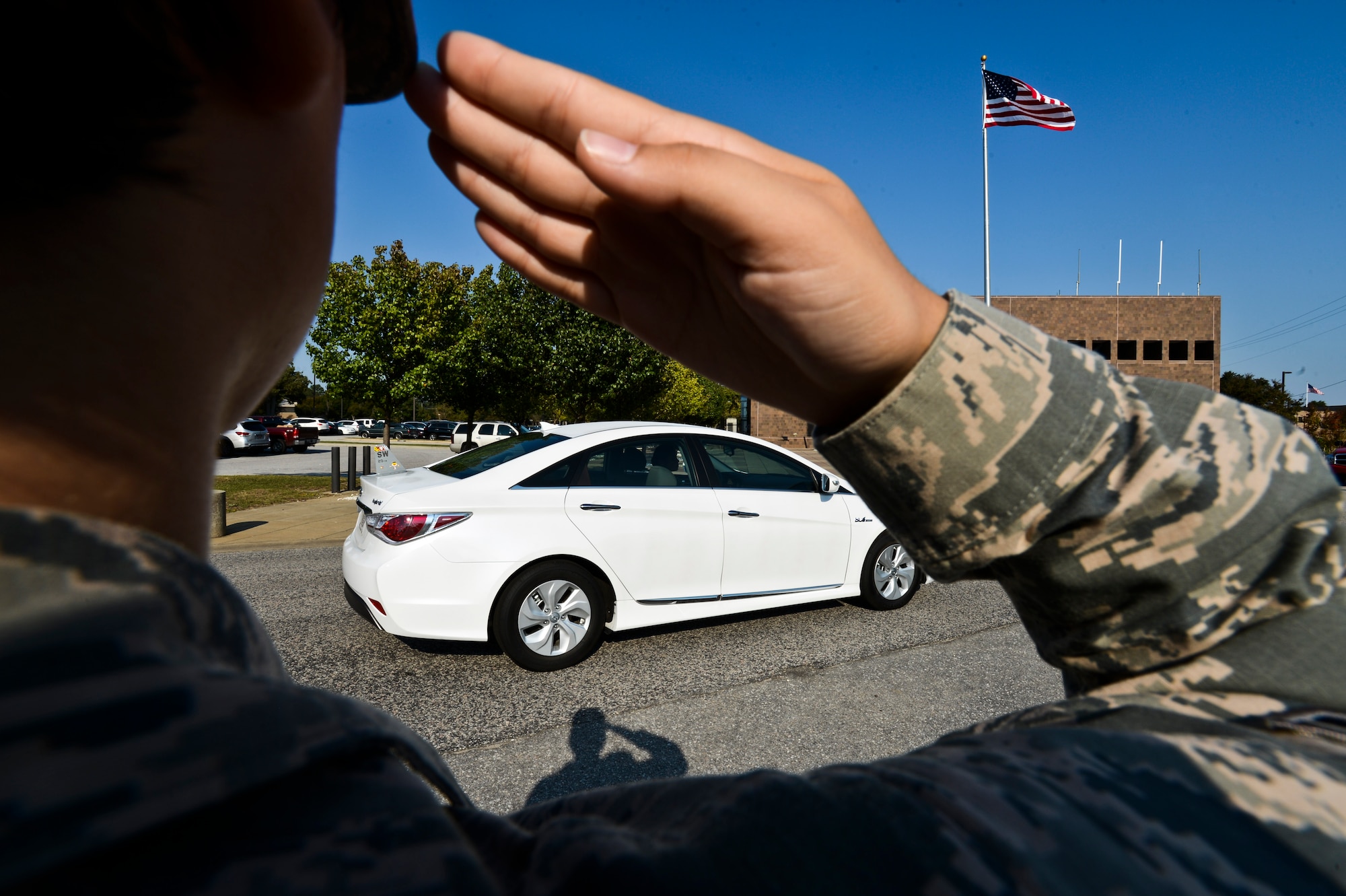 An Airman renders a salute as the 20th Fighter Wing commander’s car comes to a stop at Shaw Air Force Base, S.C., Oct. 2, 2014. U.S. Air Force Col. Stephen Jost, 20th FW commander, was assigned a new eco-friendly staff vehicle as part of an initiative based on Executive Order 13514, which mandates the reduction of petroleum use and greenhouse gases over the next 20 years in the U.S. government. (U.S. Air Force photo by Senior Airman Tabatha Zarrella/Released)