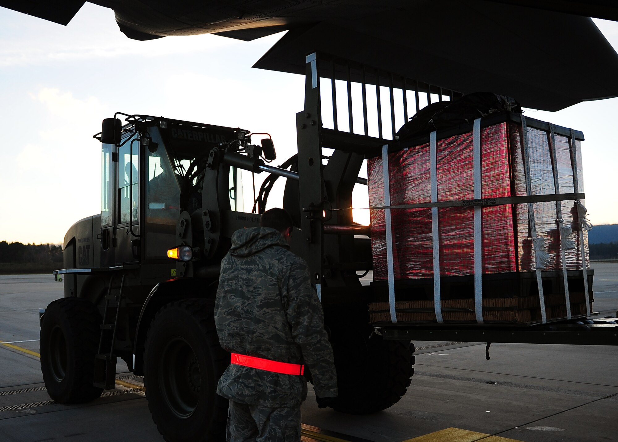 Staff Sgt. Kyle Unverfehrt, a NATO air transportation specialist from Papa Air Base, Hungary, guides toy bundles into the back of a C-130J Super Hercules on Dec. 15, 2014, Ramstein Air Base, Germany. After being loaded, the bundles will be air dropped at U.S. Army Garrison Baumholder along with Santa so that he can deliver them to local families in need of a little support this holiday season. (U.S. Air Force photo/Staff Sgt. Kris Levasseur). Kris Levasseur)