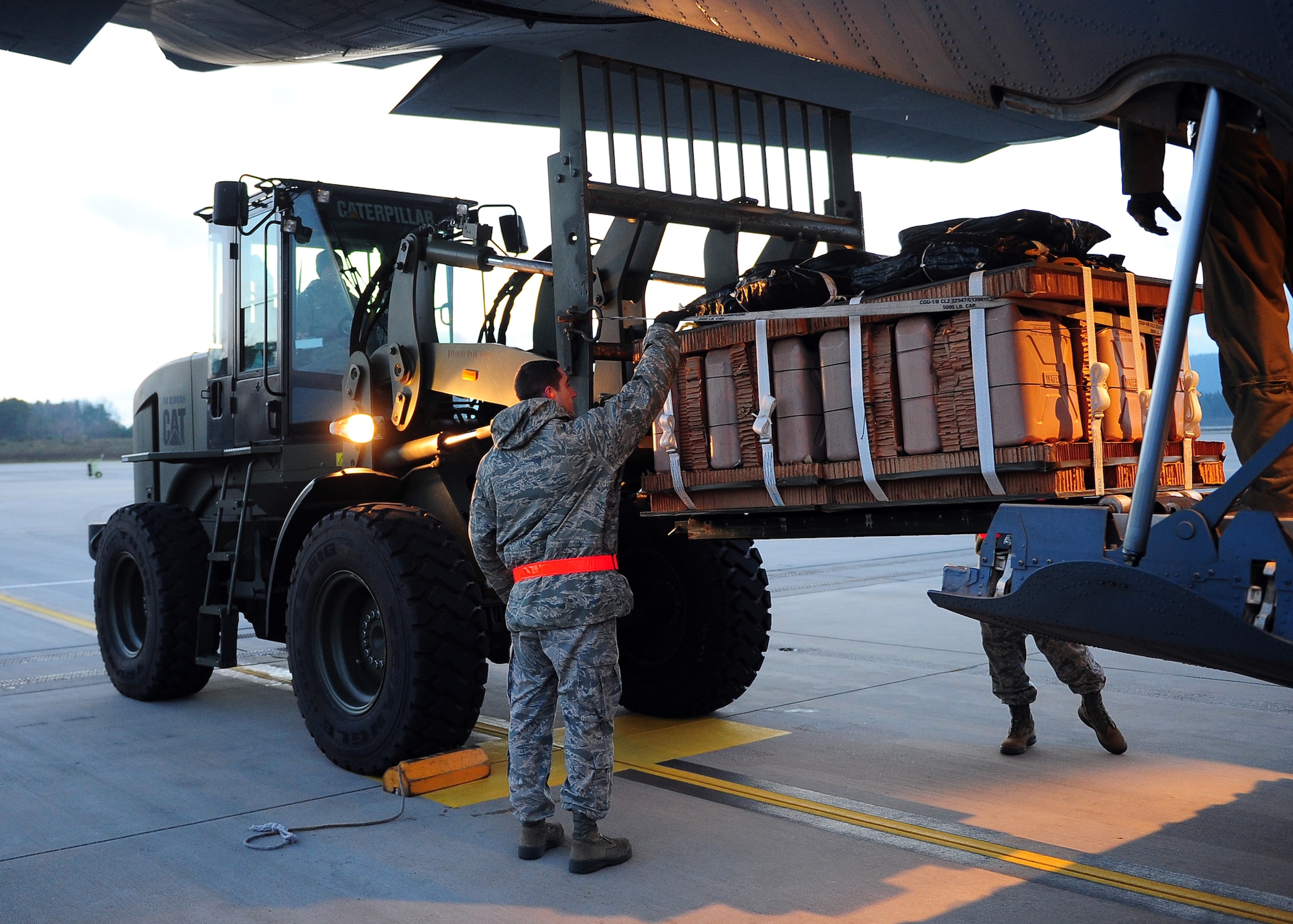Staff Sgt. Kyle Unverfehrt, a NATO air transportation specialist from Papa Air Base, Hungary, guides toy bundles into the back of a C-130J Super Hercules on Dec. 15, 2014, Ramstein Air Base, Germany. After being loaded, the bundles will be air dropped at U.S. Army Garrison Baumholder along with Santa so that he can deliver them to local families in need of a little support this holiday season. (U.S. Air Force photo/Staff Sgt. Kris Levasseur). Kris Levasseur)