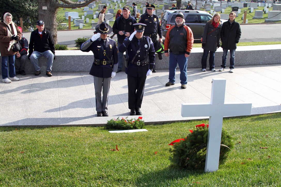 Sgt. Steven Thibodeau, left, a police officer from the town of Scarborough, Maine, and Kevin Haley, a police officer from Portland, Maine, render honors after placing a wreath at the grave marker of Edward Moore "Ted" Kennedy, U.S. Senator from Massachusetts, during Wreaths Across America at Arlington National Cemetery in Arlington, Va., Dec. 13, 2014.