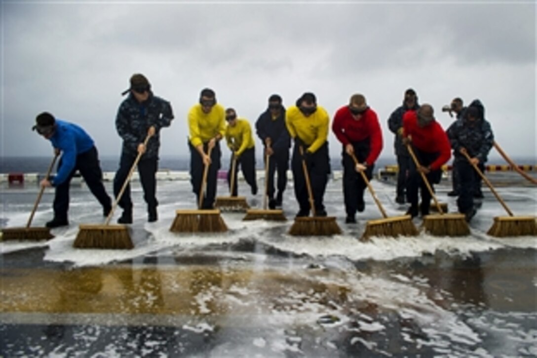 Sailors conduct a flight deck wash down aboard the amphibious assault ship USS Peleliu in the Pacific Ocean, Dec. 13, 2014. Peleliu is on its final regularly-scheduled western Pacific deployment in the U.S. 7th Fleet area of responsibility supporting security and stability in the Indo-Asia-Pacific region.