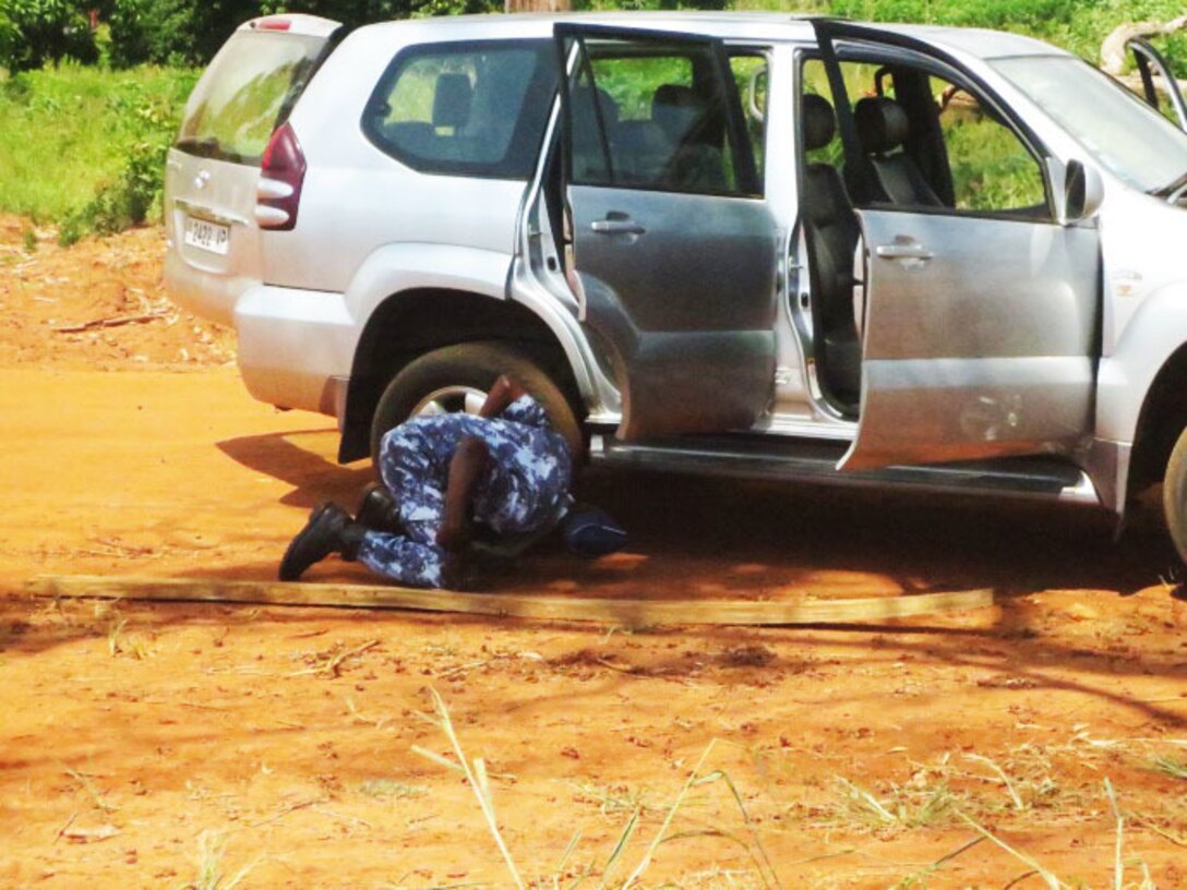 A service member with the Togolese Armed Forces inspects a wheel after the vehicle had been thoroughly searched during a theater security cooperation engagement with U. S. Marines in Lome, Togo, Dec. 4,  2014. In Togo, the Marines trained alongside 20 students from the Togoloese Army, Air Force, Navy and the Gendarmerie forces. Training in both regions focused on weapons safety and handling, rules of engagement, escalation of force, personnel and vehicle searches, vehicle entry points as well as entry control points—ending with a final exercise that tested the collective tactical knowledge learned over the course of the training engagement. Marines with SPMAGTF Crisis Response-Africa conducted the TSC engagement to help develop and enhance armed sentry skills sharing tactics, techniques and procedures with the Togolese Armed Forces. (Courtesy Photo)