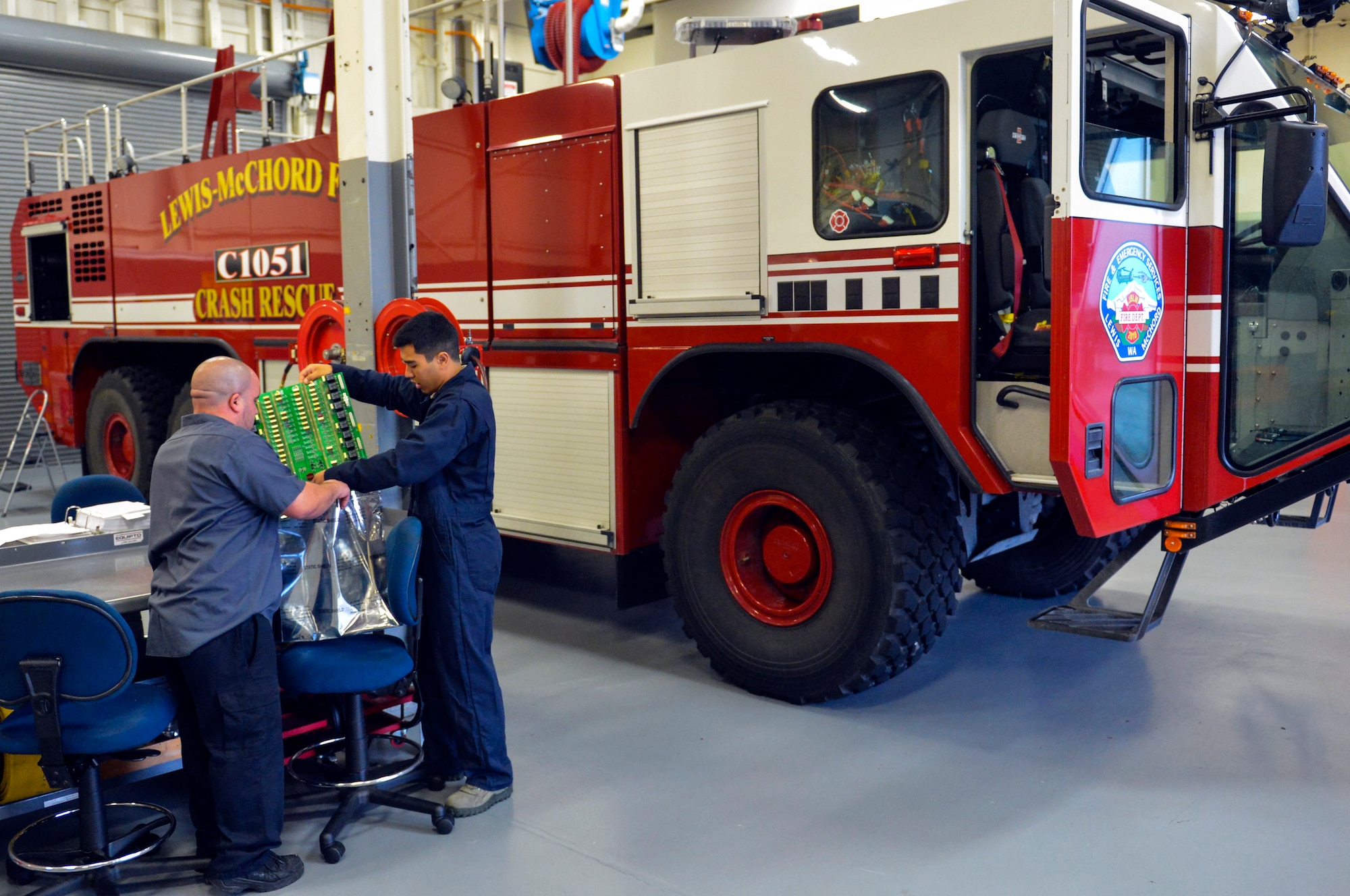 Nick DeLeon, left, and Airman 1st Class Tyler Hill package a circuit card from a rescue fire truck Dec. 9, 2014, at Joint Base Lewis-McChord, Wash. When fire truck maintainers were faced with replacing the $3,000 circuit card, they dug a little deeper into the issue and discovered a $2 solution. DeLeon is the 627th Logistics Readiness Squadron heavy mobile equipment mechanic leader and Hill is a 627th LRS fire truck maintenance journeyman. (U.S. Air Force photo/Staff Sgt. Russ Jackson)