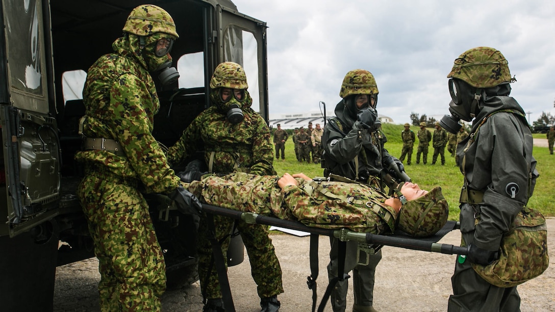 Japan Ground Self-Defense Force members with the Special Weapons Protection Unit unload a casualty during a response exercise Dec. 1 at Camp Naha, Okinawa. The training increased ties between the JGSDF and participating U.S. Marines by building trust and confidence between the two nations. The JGSDF members are with the Nuclear Biological Chemical Unit, 15th Brigade. 