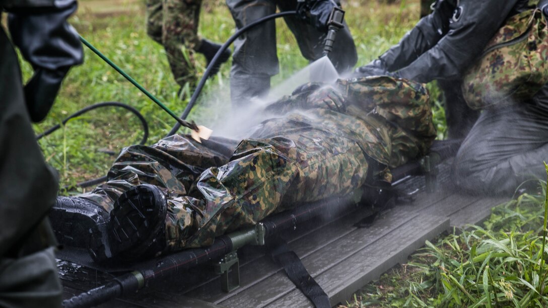 Japan Ground Self-Defense Force members with the Special Weapons Protection Unit conduct immediate decontamination on a simulated casualty Dec. 1 at Camp Naha, Okinawa. The immediate decontamination consisted of spraying a large amount of water onto the victims effected clothing and equipment. The demonstration consisted of chemical, biological, radiological and nuclear defense specialist Marines training alongside their JGSDF counterparts. 
