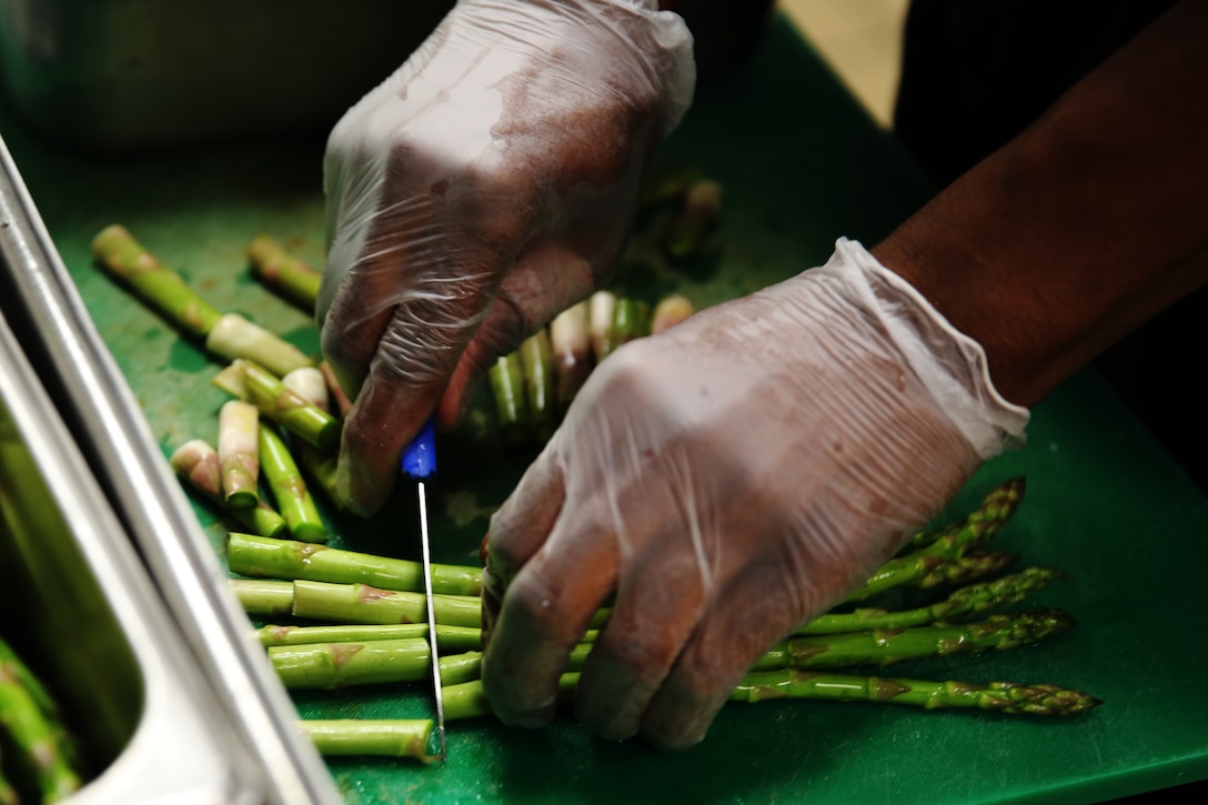 Lance Cpl. Jaylen M. Thomas chops asparagus during the Chef of the Quarter competition at Marine Corps Air Station Cherry Point, N.C., Dec. 12, 2014. Thomas prepared the winning meal of fried chicken, dirty mashed potatoes, sweet cream corn, asparagus and fried Oreos. Thomas, a native of Atlanta, is a food service specialist with Headquarters and Headquarters Squadron.