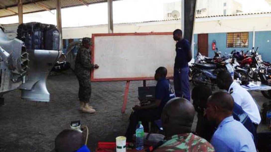 Petty Officer 3rd Class Janneh Felix conducts classroom training on outboard engines with members of the Beninese Navy in Cotonou, Benin, Nov. 18, 2014. Felix, a New York, N.Y., native, is part of a team of Marines and Coast Guardsmen from SPMAGTF Crisis Response-Africa, working alongside the Beninese Navy, trading knowledge of mechanical tactics, techniques and procedural skills while conducting engine maintenance on Honda BF225 outboard engines. 