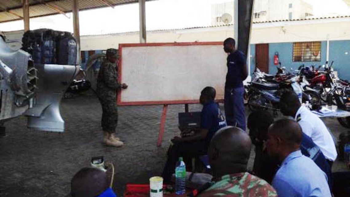 Petty Officer 3rd Class Janneh Felix conducts classroom training on outboard engines with members of the Beninese Navy in Cotonou, Benin, Nov. 18, 2014. Felix, a New York, N.Y., native, is part of a team of Marines and Coast Guardsmen from SPMAGTF Crisis Response-Africa, working alongside the Beninese Navy, trading knowledge of mechanical tactics, techniques and procedural skills while conducting engine maintenance on Honda BF225 outboard engines. 