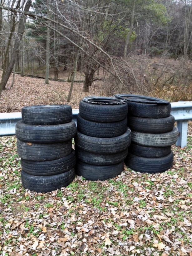 A stack of discarded tires found in a lake access parking lot.