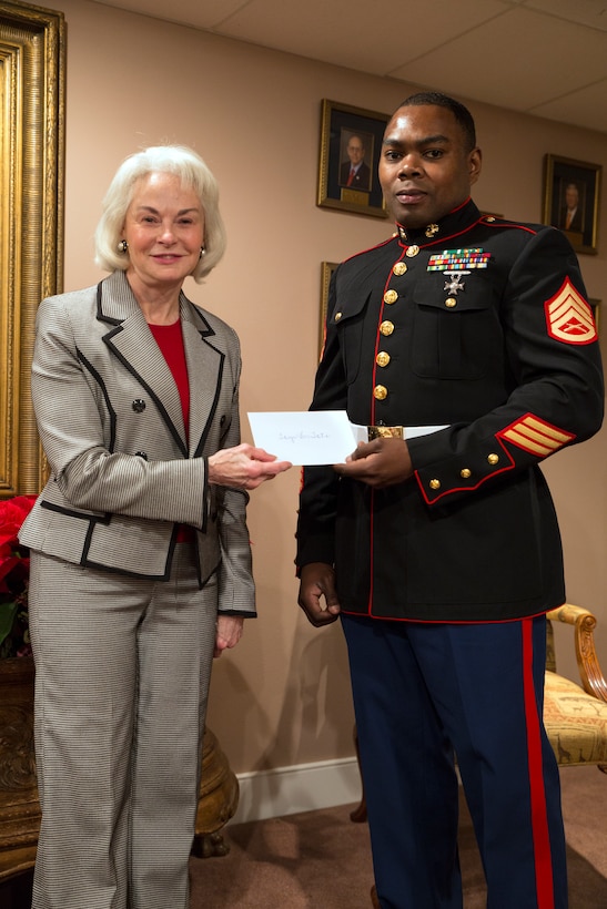 Phyllis M. Taylor (left), the chairman and president of the Patrick F. Taylor Foundation, hands Staff Sgt. Sylvester T. Dollard (right), the security administrative staff noncommissioned officer in charge at Marine Forces Reserve, a donation on behalf of foundation employees in support of the Marine Corps Reserve’s Toys for Tots program at the Patrick F. Taylor Foundation building in New Orleans, Dec. 16, 2014. Taylor has personally contributed more than $37,000 this year in support of Toys for Tots. 