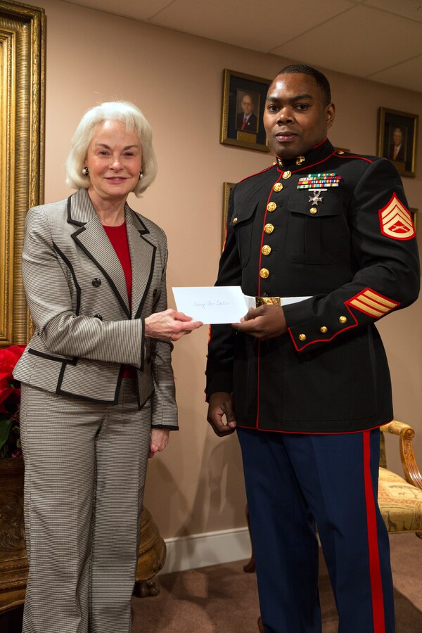 Phyllis M. Taylor (left), the chairman and president of the Patrick F. Taylor Foundation, hands Staff Sgt. Sylvester T. Dollard (right), the security administrative staff noncommissioned officer in charge at Marine Forces Reserve, a donation on behalf of foundation employees in support of the Marine Corps Reserve’s Toys for Tots program at the Patrick F. Taylor Foundation building in New Orleans, Dec. 16, 2014. Taylor has personally contributed more than $37,000 this year in support of Toys for Tots. 