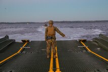 Corporal Joshua Hutton, a raft commander with Improved Ribbon Bridge platoon, Bridge Company, 8th Engineer Support Battalion, gives hand signals to steer the raft to Rhode's Point aboard Marine Corps Base Camp Lejeune, N.C., December 14, 2014. Marines with the company conducted river crossing exercises in which they transported tanks from 2nd Tank Battalion from Rhode's Point to Wells Point. (U.S. Marine Corps photo by Lance Cpl. Preston McDonald/Released)