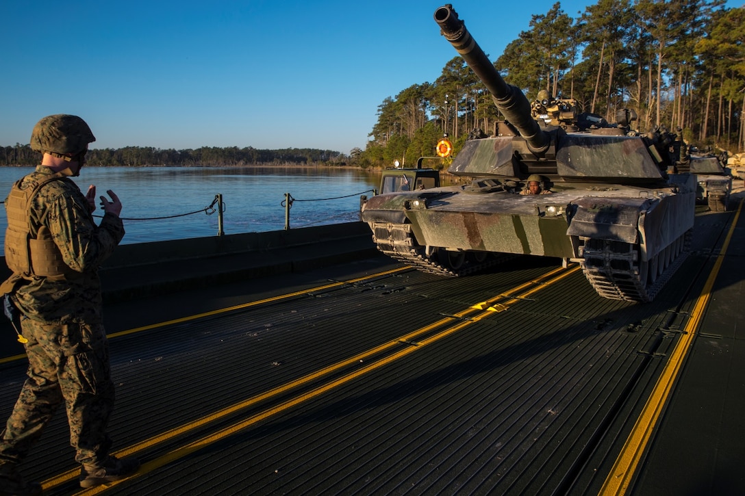 Corporal Joshua Hutton, raft commander with improved ribbon bridge platoon, Bridge Company, 8th Engineer Support Battalion, guides an M1A1 Abrams tank onto an IRB aboard Marine Corps Base Camp Lejeune, N.C., December 14, 2014. Marines with the unit conducted river crossing exercises in which they transported tanks from Rhode's Point to Wells Point. (U.S. Marine Corps photo by Lance Cpl. Preston McDonald/Released)