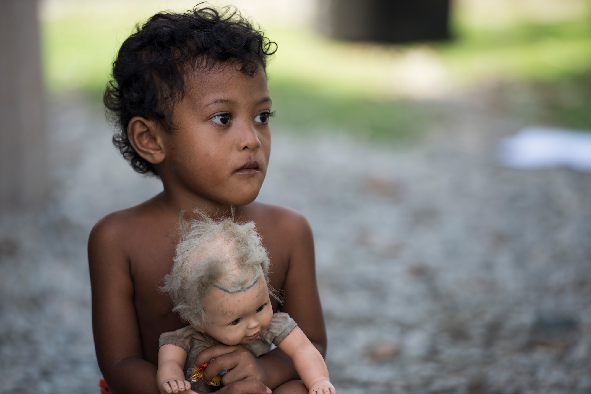 A young girl clutches her doll while watching new toys be removed from a bundle during Operation Christmas Drop at Ulithi Atoll, Micronesia, Dec. 9, 2014. Many children have no other way of receiving toys, so the airdrops mean a lot to the children and their parents, according to the island chief. (U.S. Air Force photo by Staff Sgt. Cody H. Ramirez/Released)