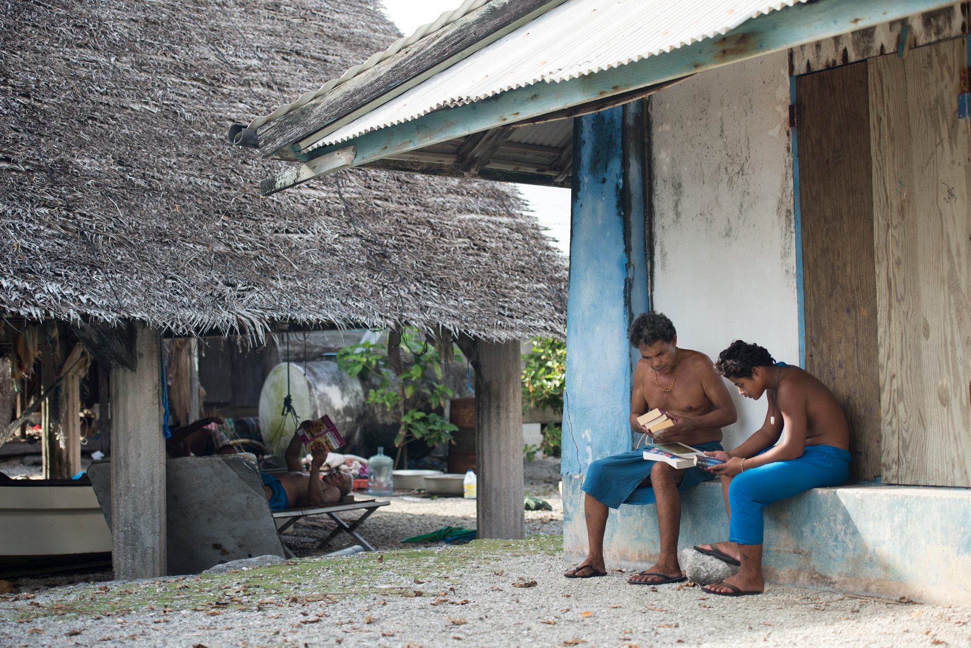 Men skim through books that were just pulled from an airdropped bundle during Operation Christmas Drop at Ulithi Atoll, Micronesia, Dec. 9, 2014. More than 50,000 pounds of donated items were airdropped to 56 islands in Micronesia during OCD 2014. (U.S. Air Force photo by Staff Sgt. Cody H. Ramirez/Released)