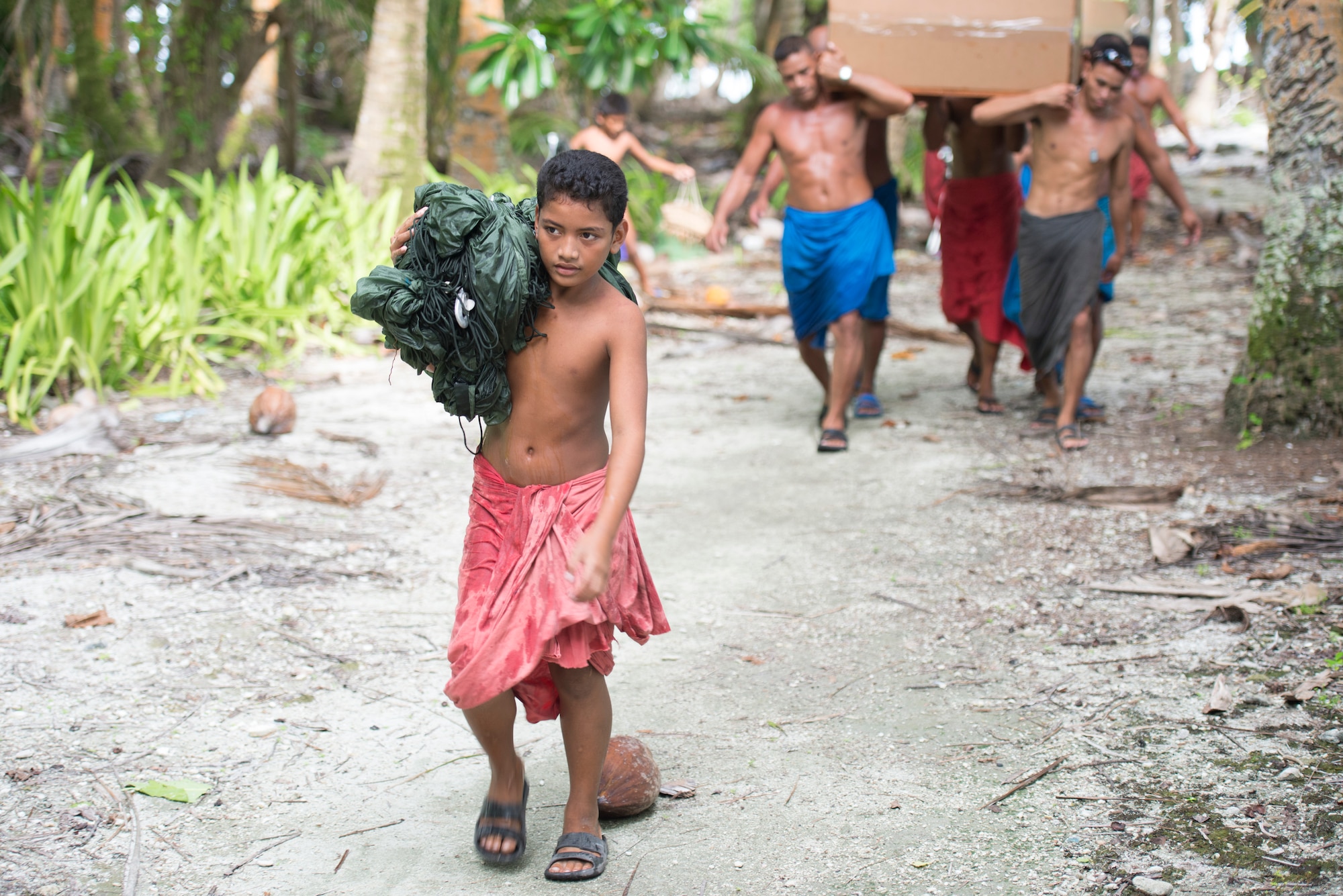 A boy carries the parachute used to drop a bundle during Operation Christmas Drop at Ulithi Atoll, Micronesia, Dec. 9, 2014. The parachute, used as a canoe sail or split between families to filter breadfruit, is one of the most treasured items given to the islanders each year. (U.S. Air Force photo by Staff Sgt. Cody H. Ramirez/Released)
