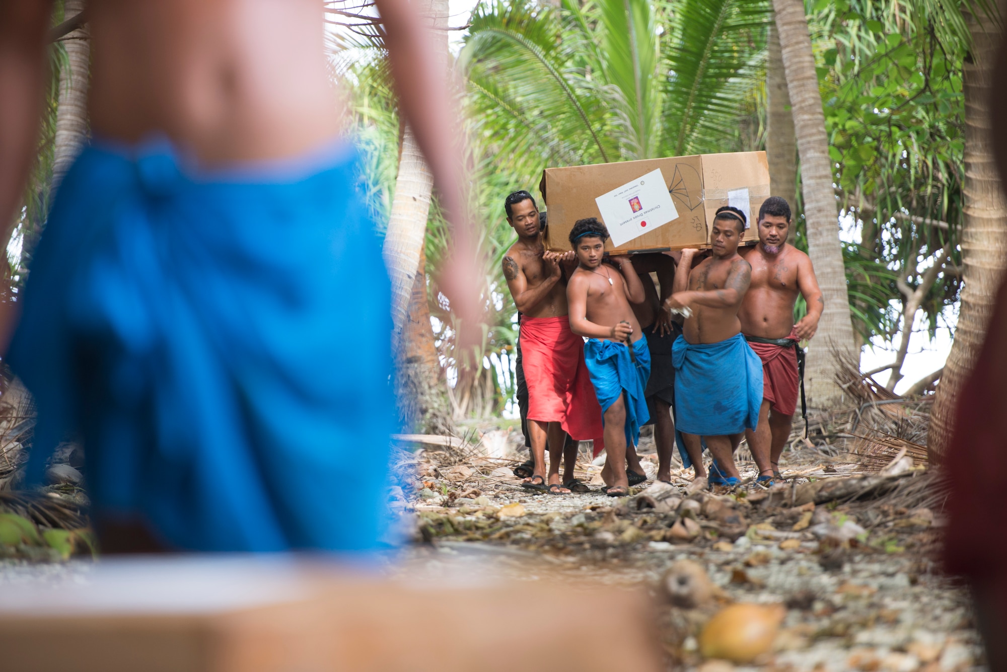 Islanders carry half of a bundle that dropped on their island during Operation Christmas Drop at Ulithi Atoll, Micronesia, Dec. 9, 2014. Ongoing for 63 years, OCD delivers supplies including, food, clothing, medicine, tools and toys to the islanders. OCD is the longest running Department of Defense humanitarian operation in history. (U.S. Air Force photo by Staff Sgt. Cody H. Ramirez/Released)