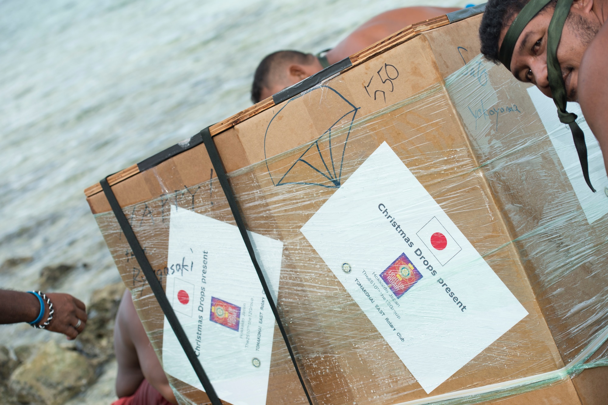 A bundle originating from Japan is lifted by islanders after being dropped from a C-130 Hercules during Operation Christmas Drop at Ulithi Atoll, Micronesia, Dec. 9, 2014. More than 90 bundles were dropped during OCD 2014, landing at 56 islands in Micronesia. (U.S. Air Force photo by Staff Sgt. Cody H. Ramirez/Released)