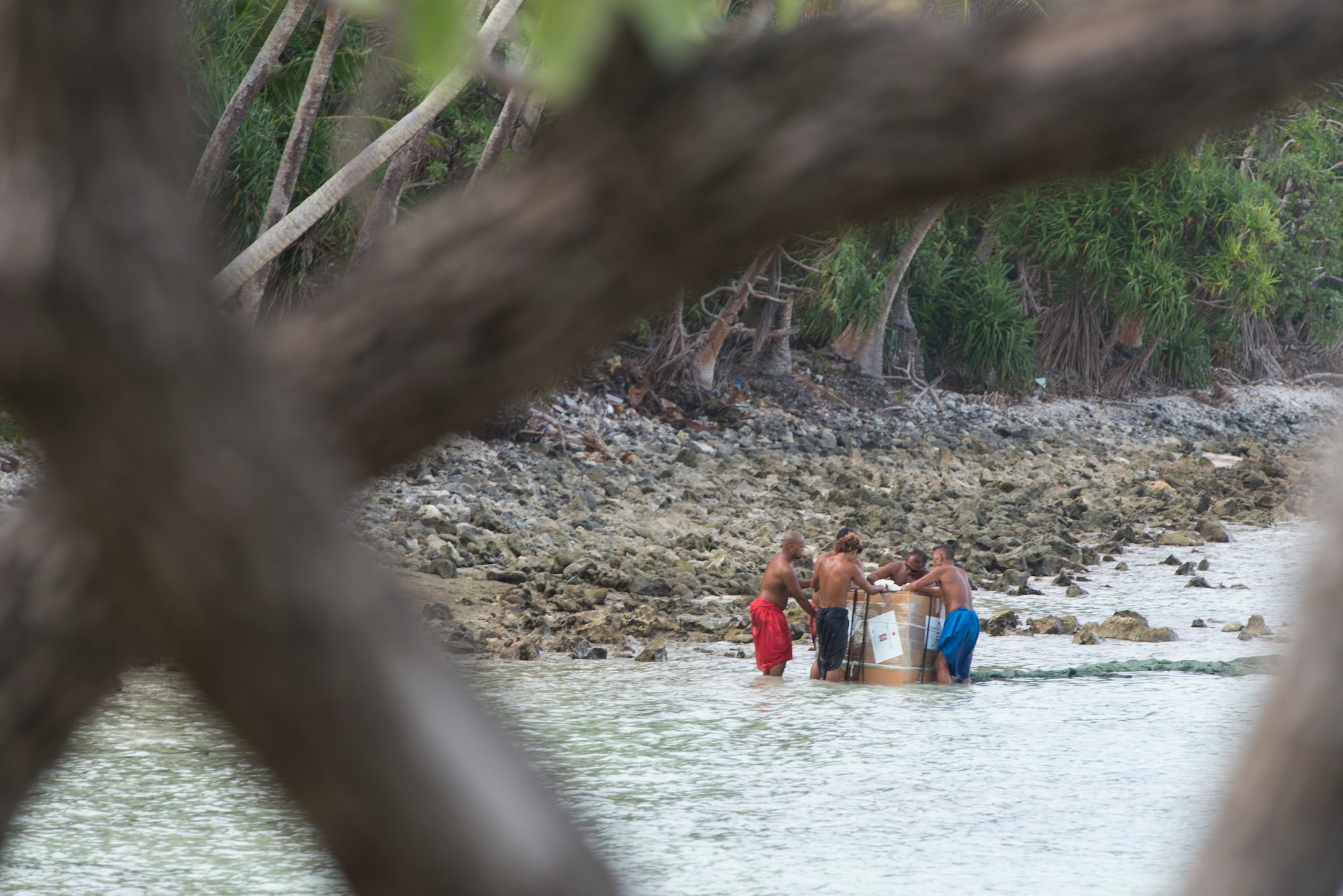Islanders rush to lift a package out of the water during Operation Christmas Drop at Ulithi Atoll, Micronesia, Dec. 9, 2014. The bundle weighed 550 pounds, bringing food, clothes, tools and toys to the island in celebration of Christmas. (U.S. Air Force photo by Staff Sgt. Cody H. Ramirez/Released)