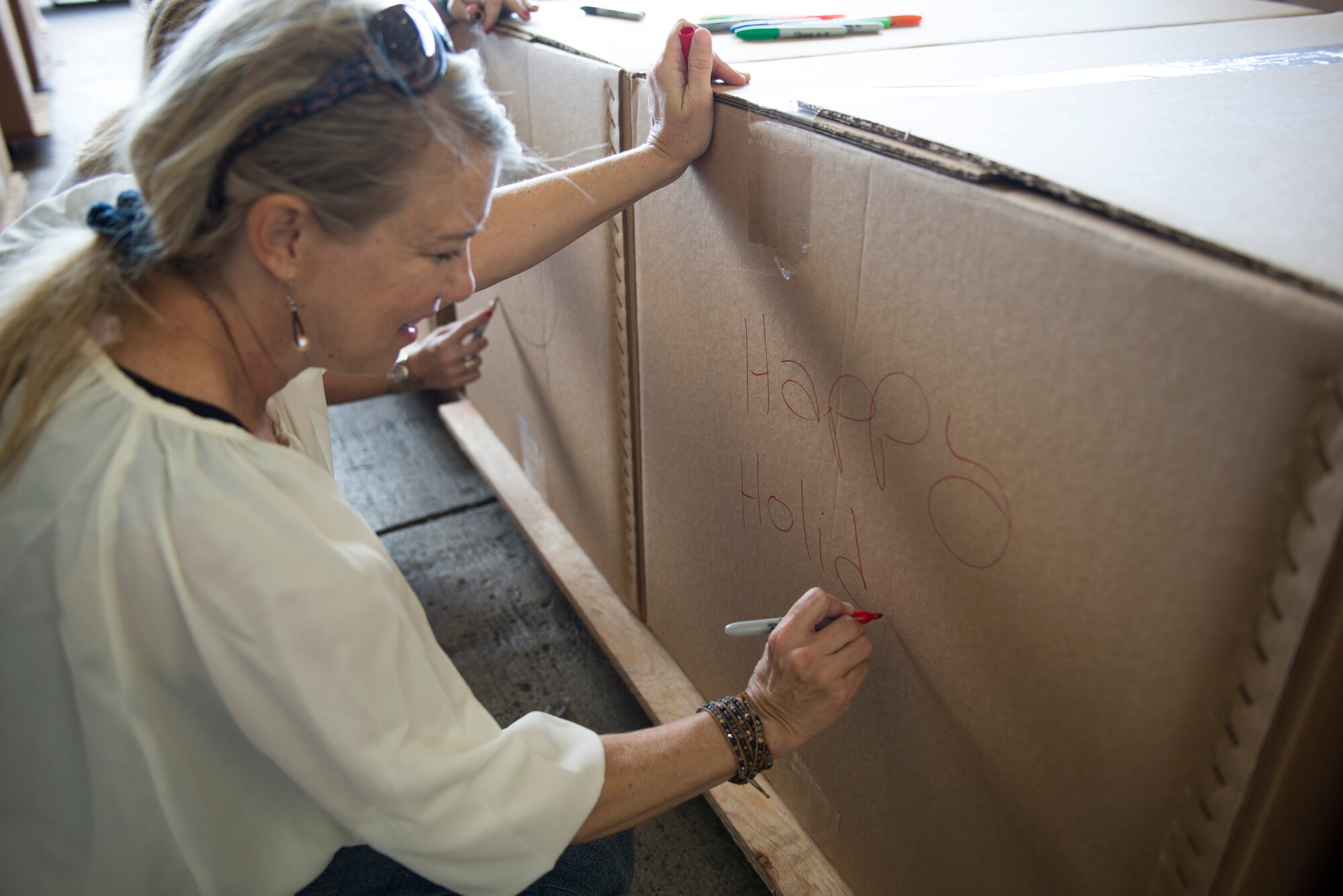 A volunteer assists with decorating boxes destined for Micronesia during Operation Christmas Drop at Andersen Air Force Base, Guam, Dec. 06, 2014. Volunteers and members from Andersen and Yokota Air Base, Japan, came together to organize, water-proof, package and decorate bundles containing more than 50,000 pounds of donated items. (U.S. Air Force photo by Staﬀ Sgt. Cody H. Ramirez/Released)