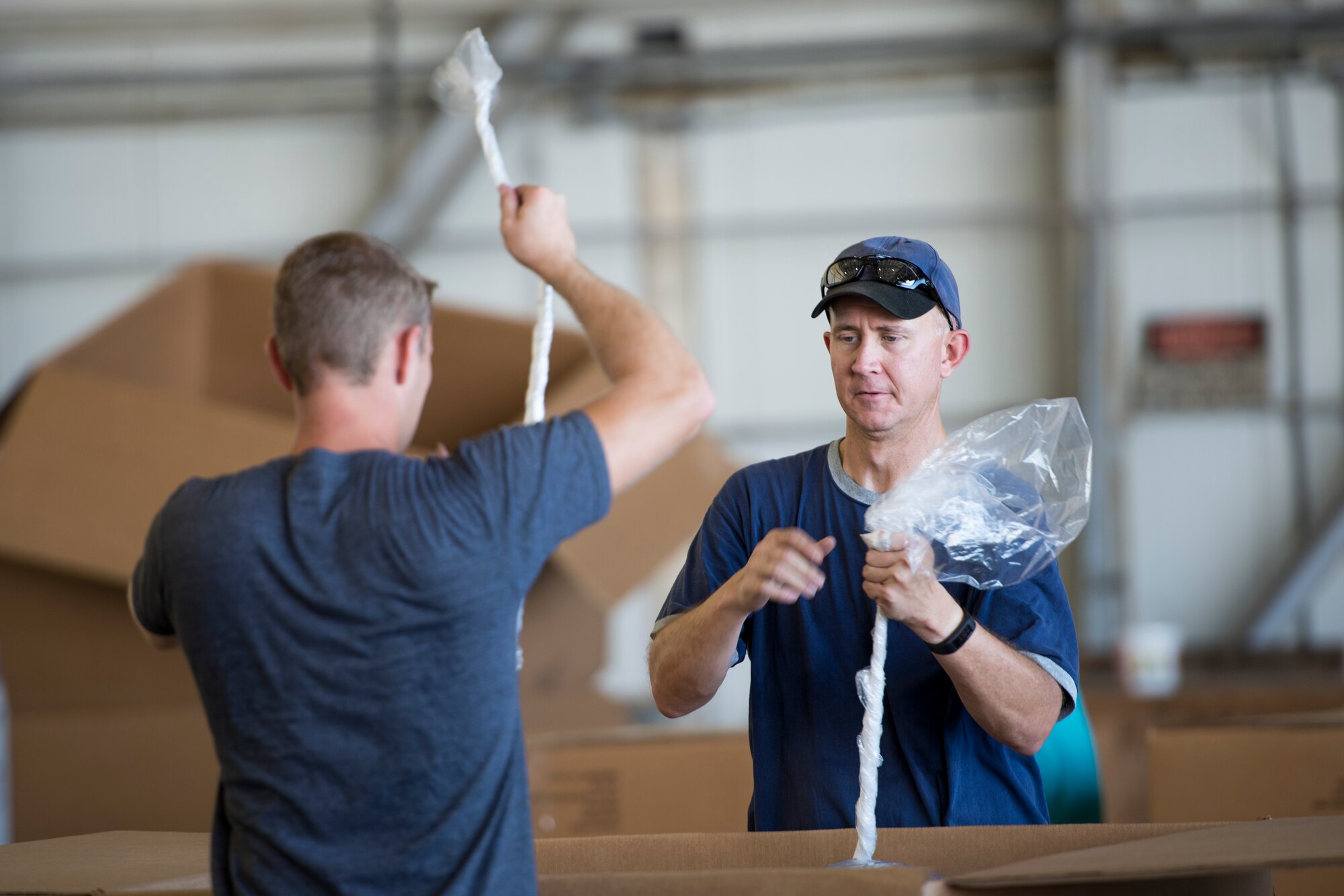 Two volunteers tie plastic bags while water- proofing donations during Operation Christmas Drop at Andersen Air Force Base, Guam, Dec. 06, 2014. The more than 50,000 pounds of donated goods were water- proofed to ensure rice and other items in the bundle do not spoil. (U.S. Air Force photo by Staﬀ Sgt. Cody H. Ramirez/Released)