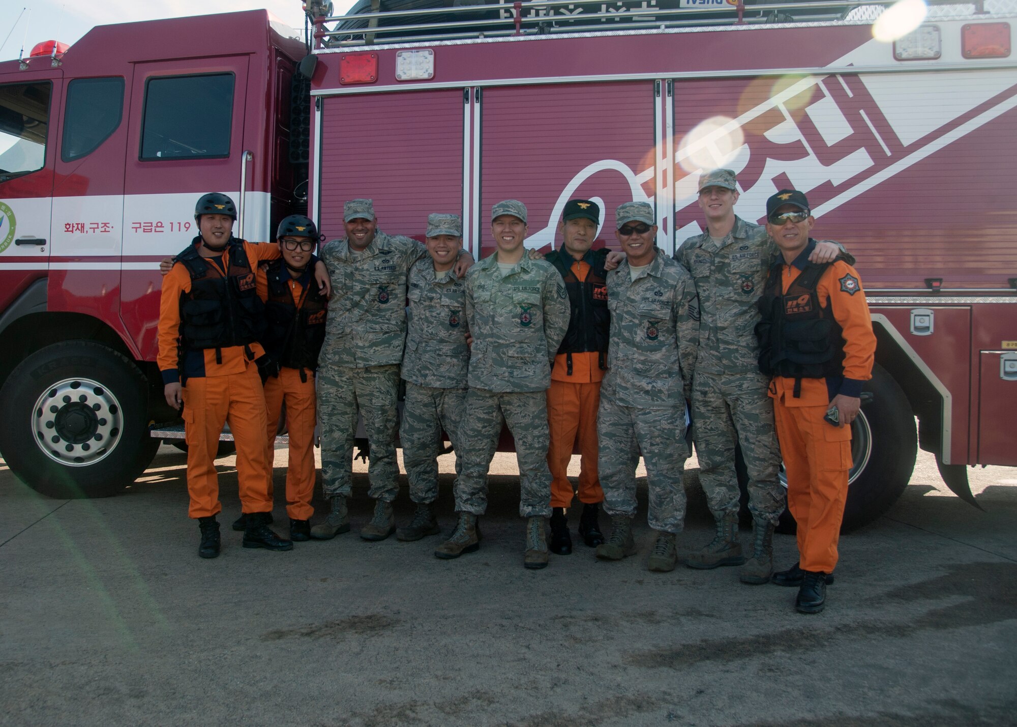 Kunsan Air Base and Gunsan City firefighters pose for a group photo together during an emergency-relief exercise in Gunsan City, Republic of Korea, Nov. 5, 2014. The purpose of the exercise was to establish an incident command system between multiple organizations and enhance their ability to respond to emergencies and large disasters. (U.S. Air Force photo by Senior Airman Taylor Curry/Released)