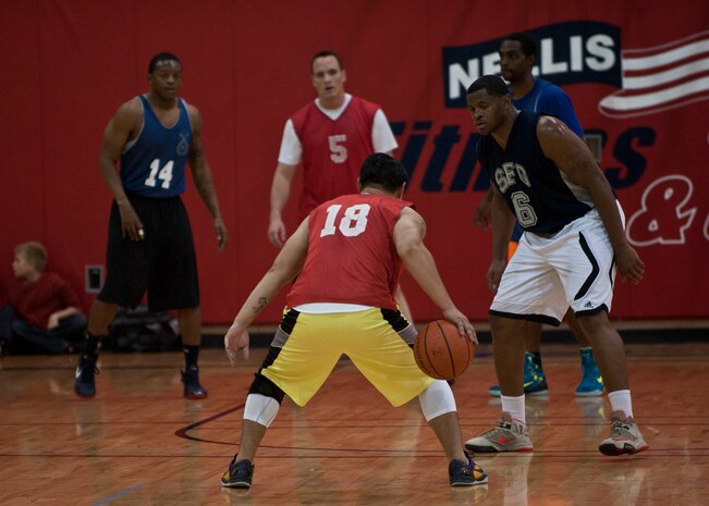 A member of the 57th Operations Support Squadron looks for an open teammate during an intramural basketball game against the 99th Security Forces Squadron at Nellis Air Force Base, Nev., Dec. 15, 2014. After being stymied by the 99th SFS defense in the first half, the 57th came within 10 points in the second before the 99th SFS pulled away late in the game. The 57th OSS is now on a three game losing streak and the 99th SFS improves to 1-1 to open the intramural basketball season, which kicked off at Nellis AFB Dec. 8. (U.S. Air Force photo by Staff Sgt. Siuta B. Ika)