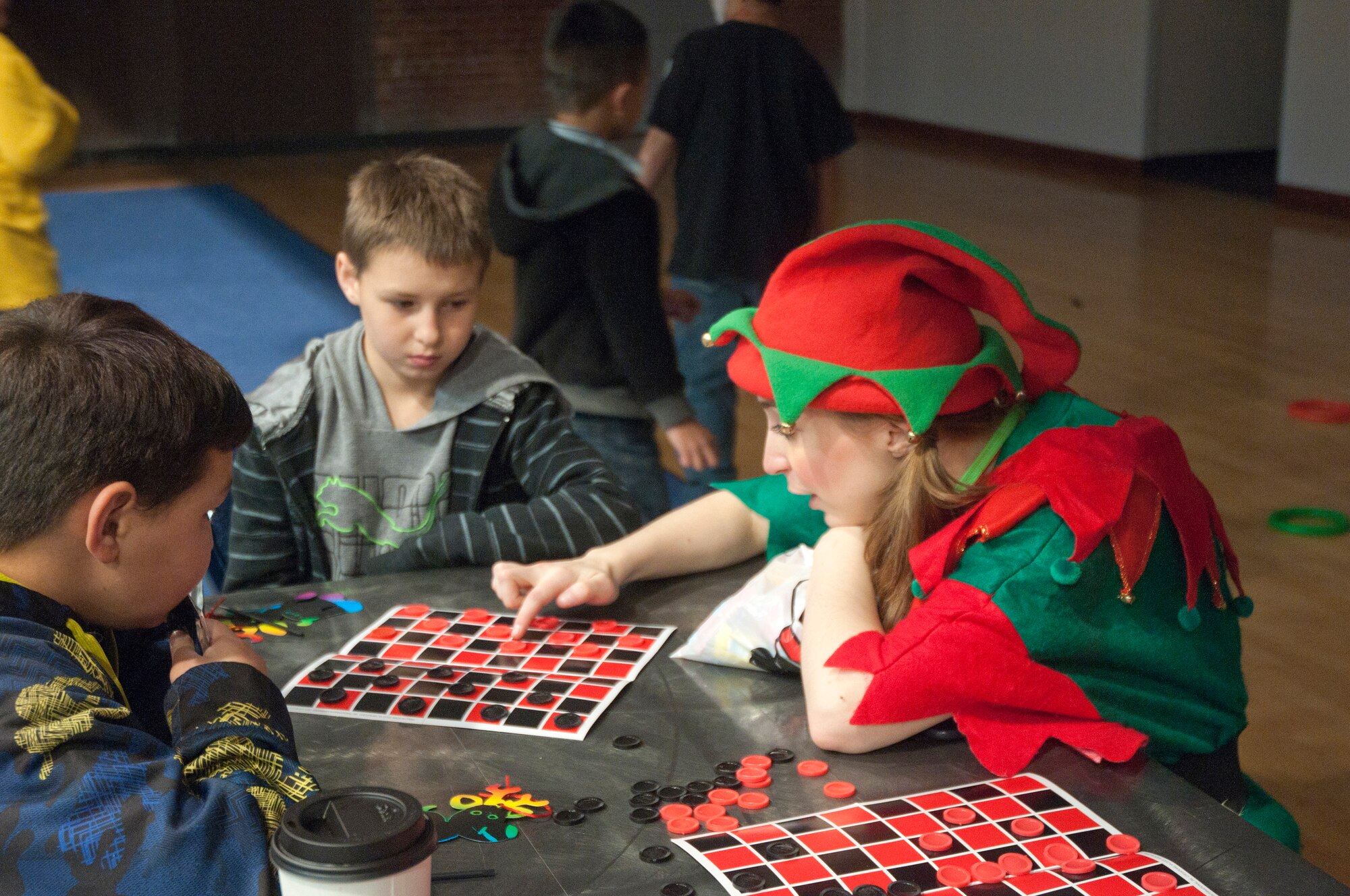 2nd Lt. Lindsey Byrd, 321st Missile Squadron deputy combat crew commander, teaches children how to play checkers during Operation Provide Joy in the Fall Hall Community Center Dec. 13, 2014, on F.E. Warren Air Force Base, Wyo. Several volunteers played the role as elves and encouraged children to be involved in activities and games during the event. (U.S. Air Force photo/Airman 1st Class Malcolm Mayfield)