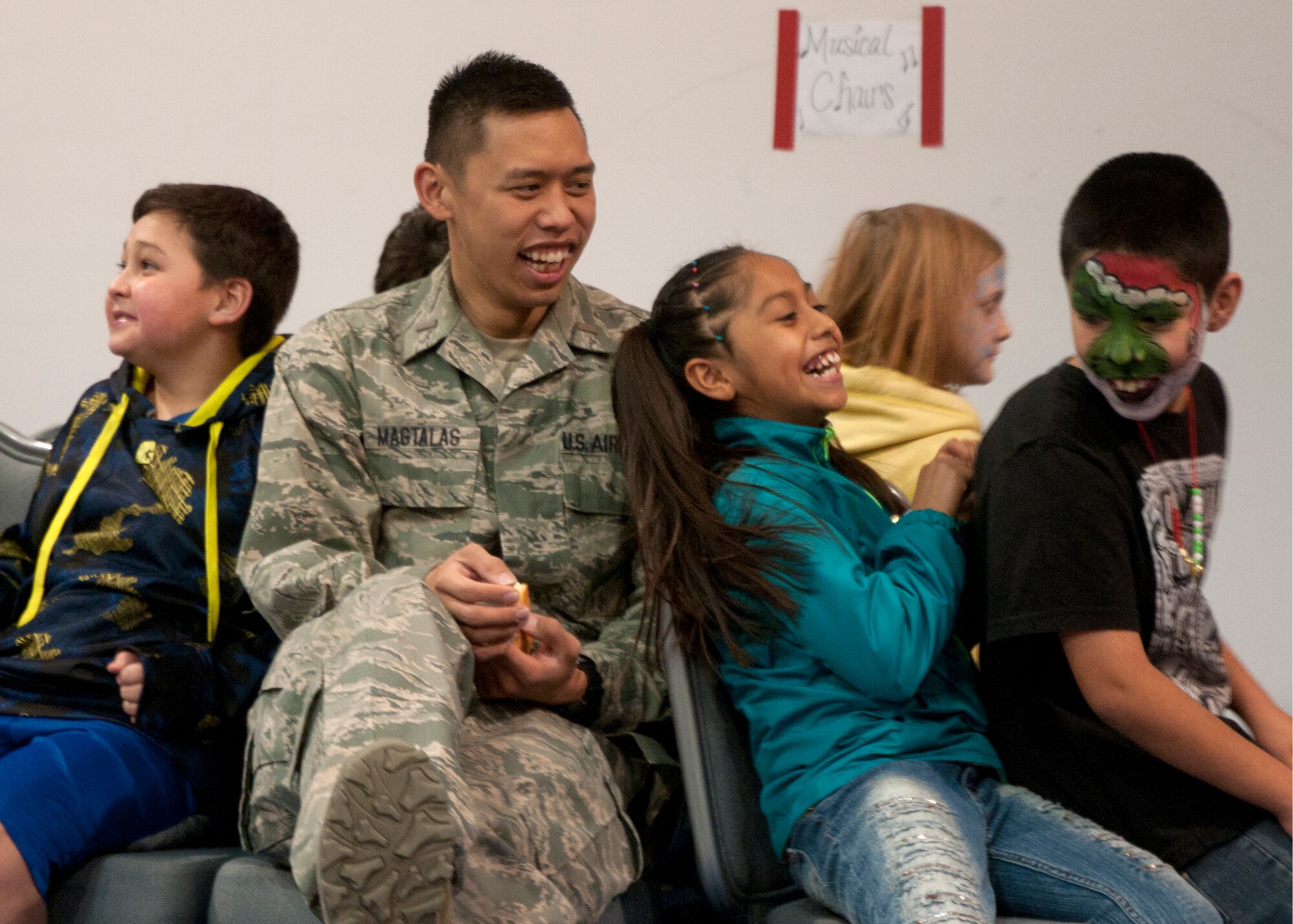 2nd Lt. Brandon Magtalas, 320th Missile Squadron deputy combat crew commander, participates in musical chairs with children during Operation Provide Joy in the Fall Hall Community Center Dec. 13, 2014, on F.E. Warren Air Force Base, Wyo. Volunteers actively participated in activities with children, making each event more lively. (U.S. Air Force photo/Airman 1st Class Malcolm Mayfield)