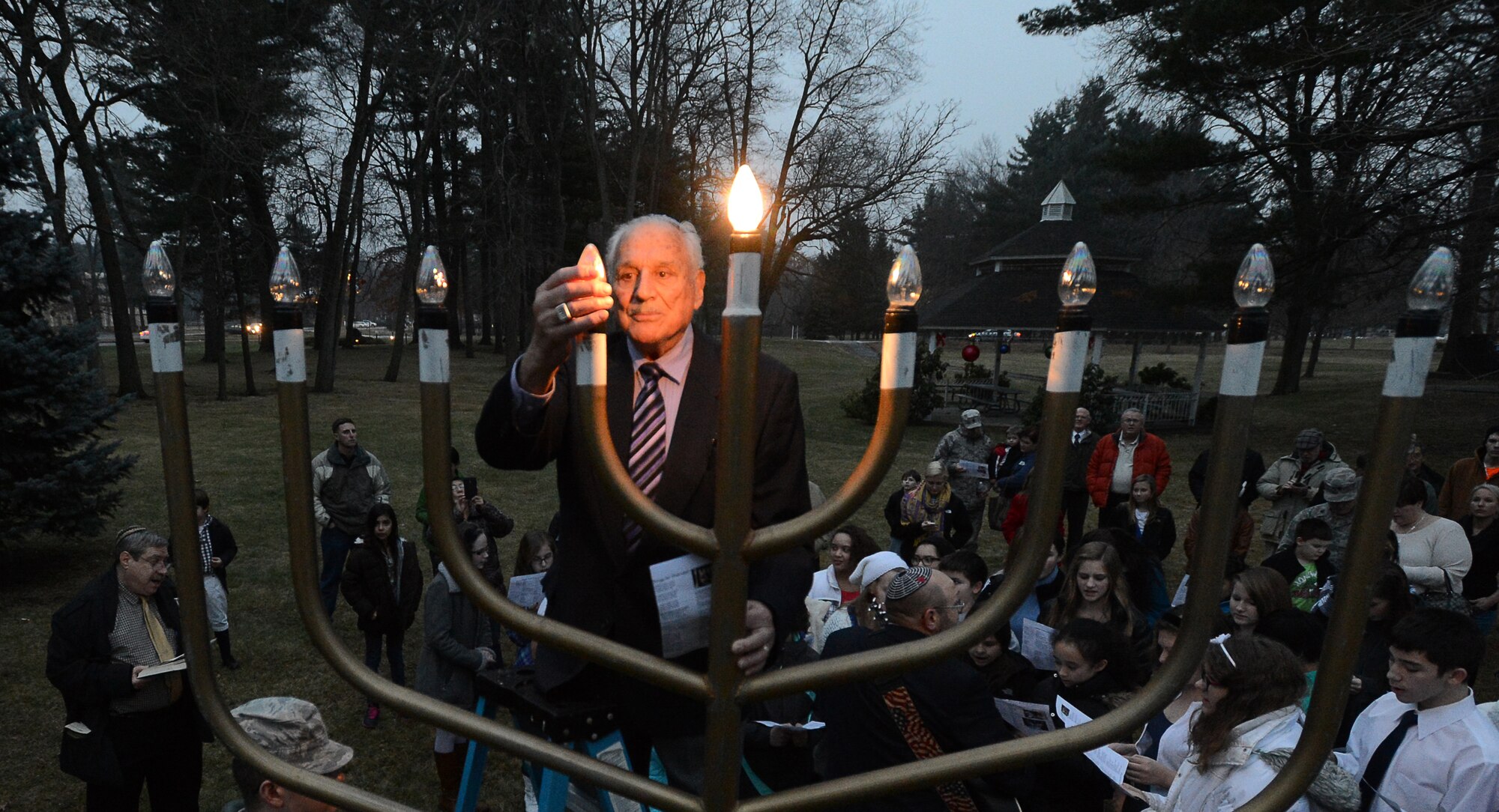 Rabbi Abraham Morhaim lights the menorah as members of the Hanscom Air Force Base, Mass. community gather at the chapel to observe Hanukkah, Dec. 16. The menorah lighting commemorates the eight-day celebration of Hanukkah, Dec. 16 through Dec. 24, also known as the Festival of Lights. During each night of the festival an additional candle is lit.  (U.S. Air Force photo by Jerry Saslav)   