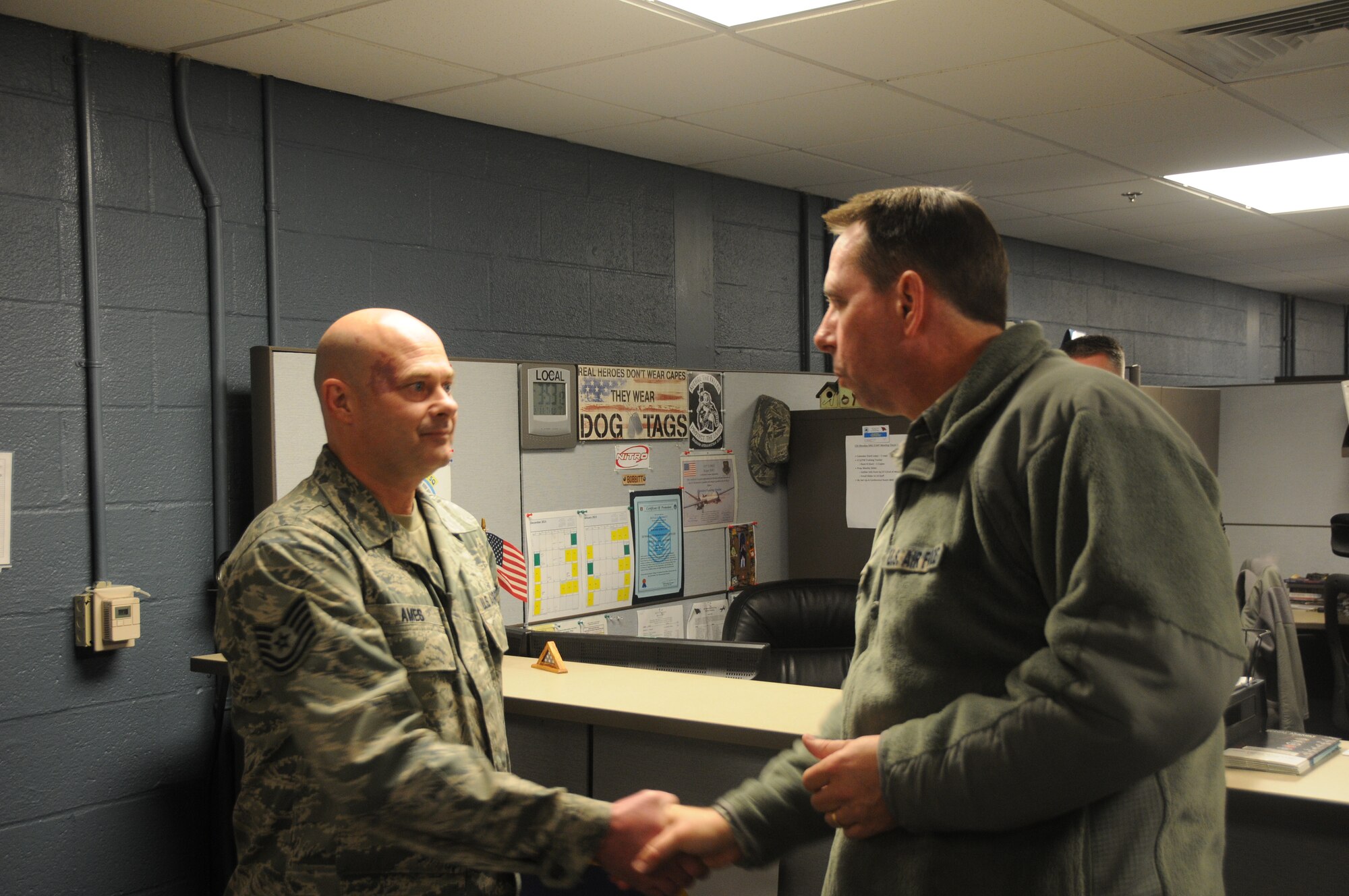 Tech. Sgt. Jeffery Ames, a member of the 153rd Intelligence Squadron, is coined by Maj. Gen. John Shanahan, commander of the 25th Air Force, at Ebbing Air National Guard Base, Fort Smith, Ark., Dec. 11, 2014. Shanahan’s visit encompassed seeing and understanding how the wing’s new mission aligns with the 25th AF. (U.S. Air National Guard photo by Airman 1st Class Cody Martin/released)