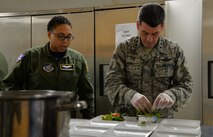Staff Sgt. Aisya Hinson, 65th Airlift Squadron flight attendant and chef, shows Lt. Gen. Russell Handy, 11th Air Force commander, the proper way to dress a plate with a salad before lunch with squadron commanders at Joint Base Pearl Harbor-Hickam, Hawaii, Dec. 12, 2014. During his visit, Handy hosted a Wing all-call, met with group and squadron leadership and toured base units. (U.S. Air Force photo by Staff Sgt. Alexander Martinez/Released)      
