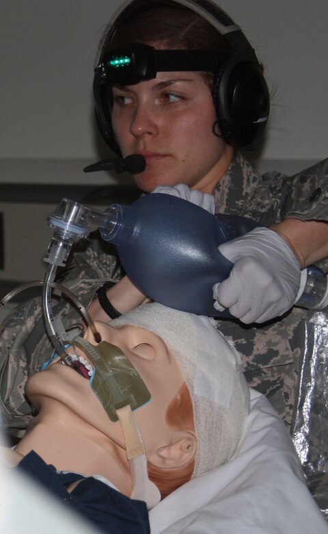 Respiratory therapist Air Force Staff Sgt. Jamie Bucher works to improve the breathing of a "patient" during Critical Care Air Transport Team (CCATT) Simulation Day training in Walter Reed Bethesda simulation center on Dec. 11. The "patient" had a closed head injury and bleeding in his brain, requiring invasive monitoring of his intracranial pressure, explained flight physician Capt. Katherine Ellis. "He also had lung injuries and arm and leg fractures. During the 'flight,' his ET tube became clogged and he required re-intubation," she added.  (Photo by Bernard S. Little)