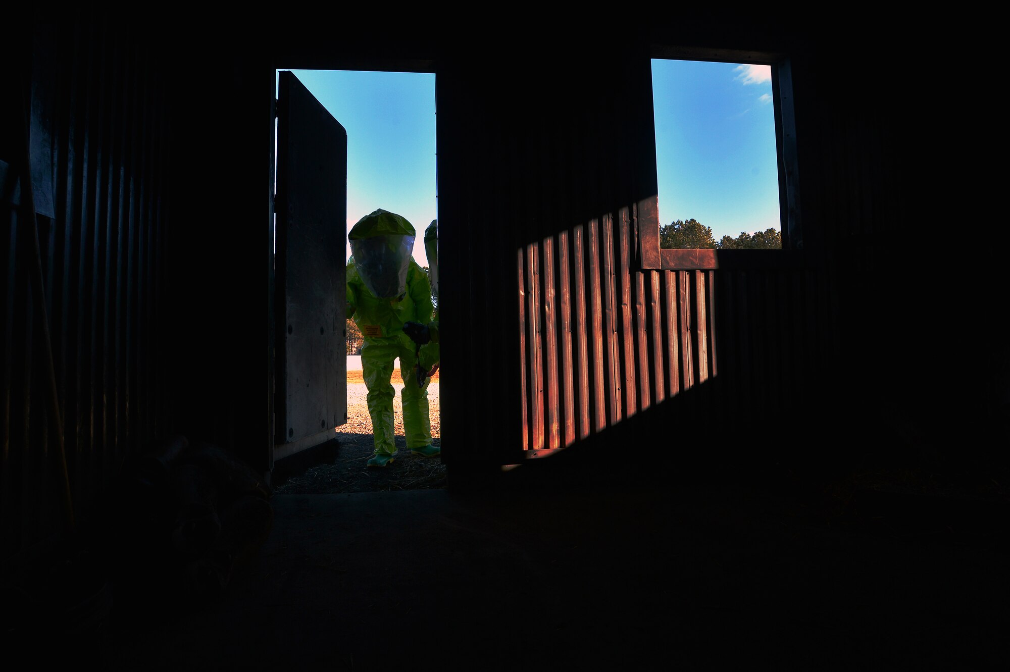 U.S. Air Force Senior Airman Chantal Hogue, 20th Civil Engineer Squadron emergency management apprentice, and Senior Airman Brandon Burgess, 20th Aerospace Medicine Squadron bioenvironmental engineering journeyman enter a simulated contaminated building in search of a chemical agent during an integrated base emergency response capability exercise at Shaw Air Force Base, S.C., Dec. 10, 2014. After the Airmen found the hazardous materials they radioed to their team record the findings. (U.S. Air Force photo by Staff Sgt. Kenny Holston/Released)