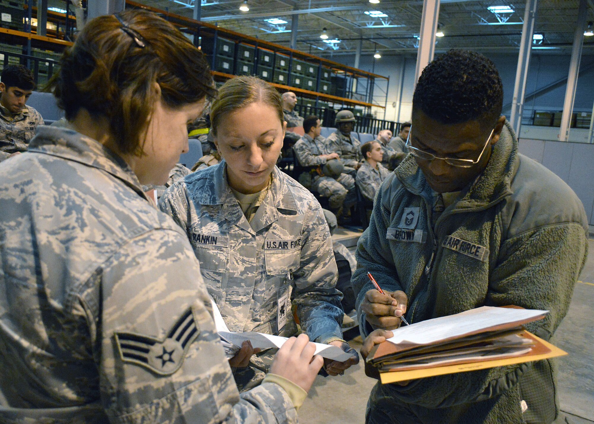 Air Force Staff Sgt. Barbara Rankin, center, and Senior Master Sgt. Johnny Brown, right, both assigned to the 43rd Logistics Readiness Squadron, complete personnel deployment function exercise forms on Dec. 16 at Pope Army Airfield, North Carolina. The Group participated in a deployment exercise here Dec. 12 thru Dec. 16 as part of the new Air Force Commander’s Inspection Program. The deployment exercise focused on the Group’s ability to deploy over 100 expeditionary Airmen and equipment worldwide on short-notice. (U.S. Air Force photo/Marvin Krause)