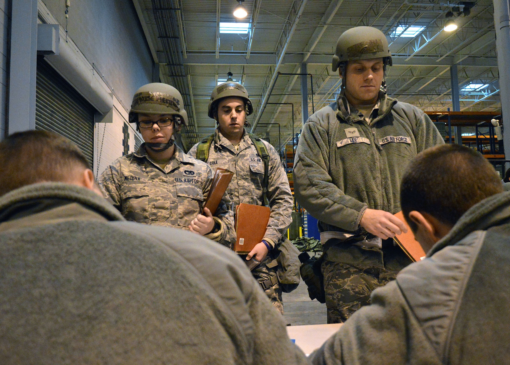 Air Force Airman 1st Class Denise Medina, left, Senior Airman Joseph Cole, center, and Senior Airman Kyle Lee, right, all assigned to the 43rd Logistics Readiness Squadron, are added to the exercise passenger manifest by personnel deployment function personnel on Dec. 16 at Pope Army Airfield, North Carolina. The Group participated in a deployment exercise here Dec. 12 thru Dec. 16 as part of the new Air Force Commander’s Inspection Program. The deployment exercise focused on the Group’s ability to deploy over 100 expeditionary Airmen and equipment worldwide on short-notice. Passenger manifests are prepared for each chalk to ensure in-transit visibility from point of origin to final destination. (U.S. Air Force photo/Marvin Krause)