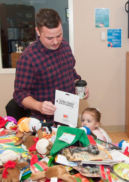 Senior Airmen Taylor Beams, 3d Airlift Squadron loadmaster, and his daughter select a toy from a table of donated gifts Dec. 13, 2014, at the Youth Center on Dover Air Force Base, Del. The toys were on display during the First Sergeants Council’s Wing Children's Holiday Party as well as crafts and bouncy castles. (U.S. Air Force photo/Senior Airman Jared Duhon)
