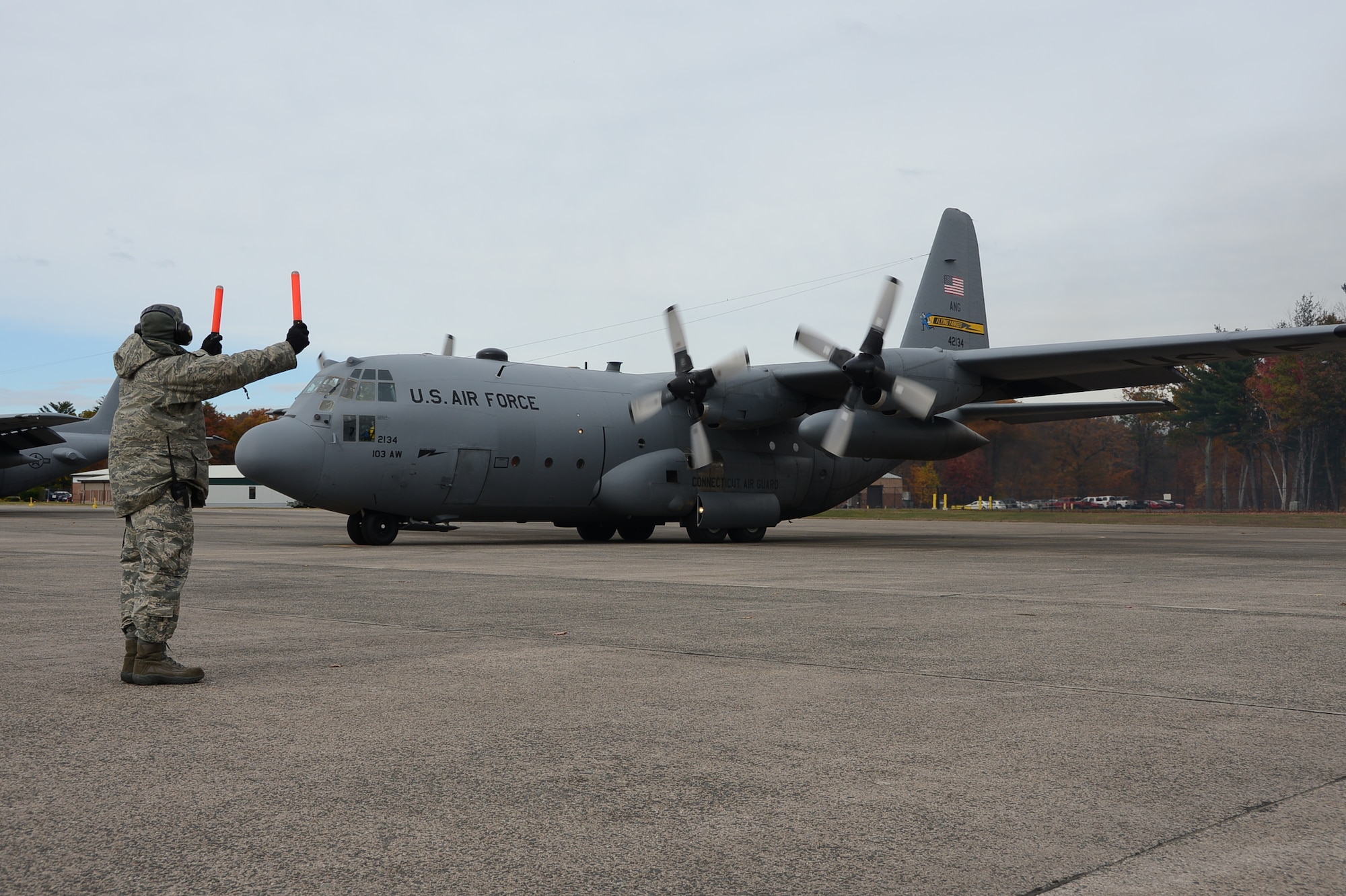 Tech. Sgt. Jonathon Fiore, a crew chief assigned to the 103rd Maintenance Group directs aircrew members aboard a C-130H Hercules aircraft assigned to the 103rd Airlift Wing as the aircraft begins to taxi just before takeoff.  Maintainers configured the aircraft, along with another, as part of the unit’s first C-130H engine generation exercise, Nov. 1, 2014 at Bradley Air National Guard Base, East Granby, Conn.  The mission for the aircraft may involve transporting passengers, cargo, a combination of both, or flying through hostile territory. Depending on the mission, the generation may include aircraft inspections and servicing, seating for passengers, cargo configuration, and loading armor or chaff flare, said Master Sgt. Jonas Concepcion, production superintendent for the 103rd Maintenance Group.  (U.S. Air National Guard photo by Maj. Bryon M. Turner)