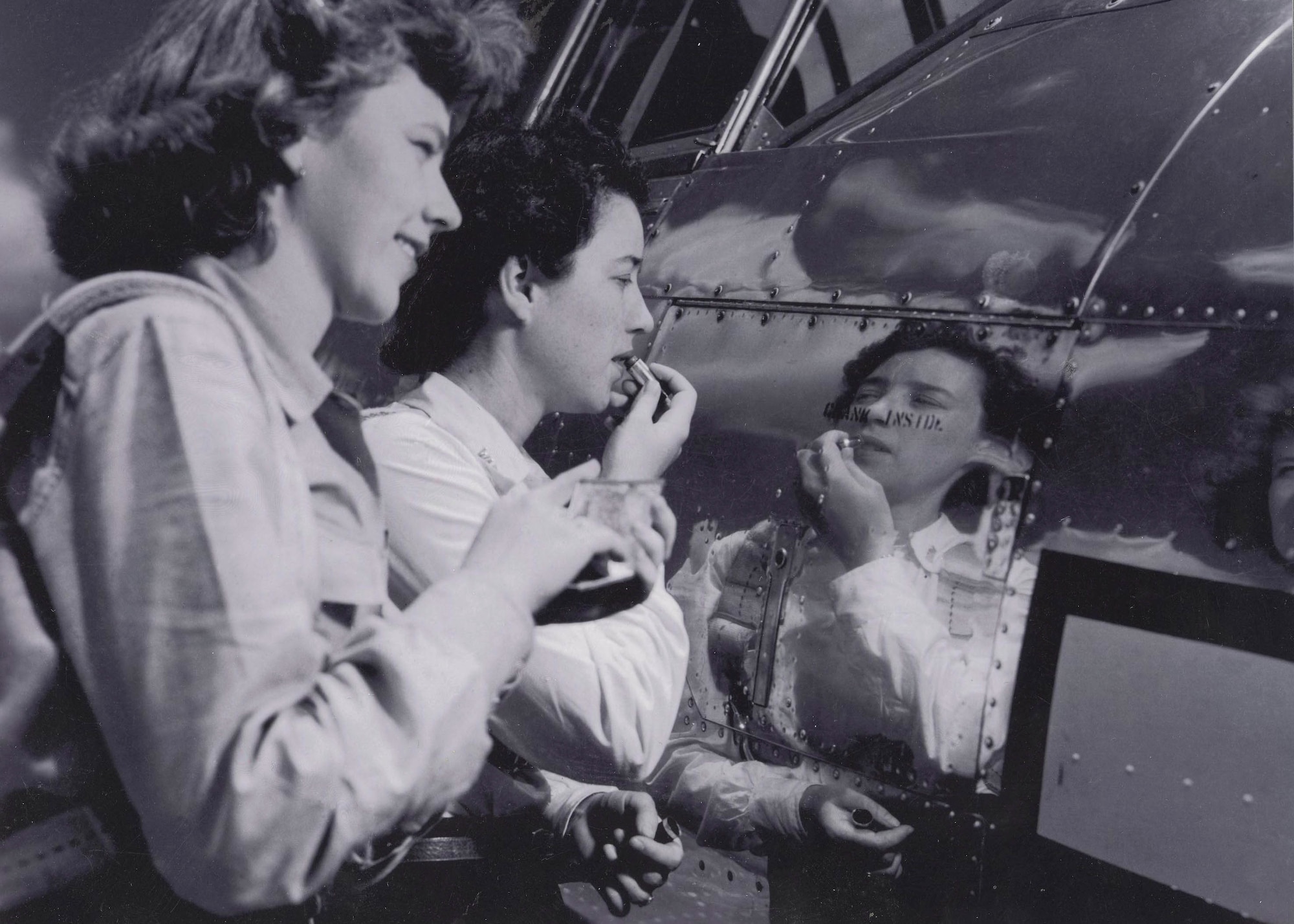 W.A.S.P.s Flora Belle (Smith) Reece and Dorothy Allen put on make up in the reflection of a P-38. In her 90 years, Reece only wore lipstick, but posed for the photo with make up when asked to by a newspaper photographer. (U.S. Air Force photo)
