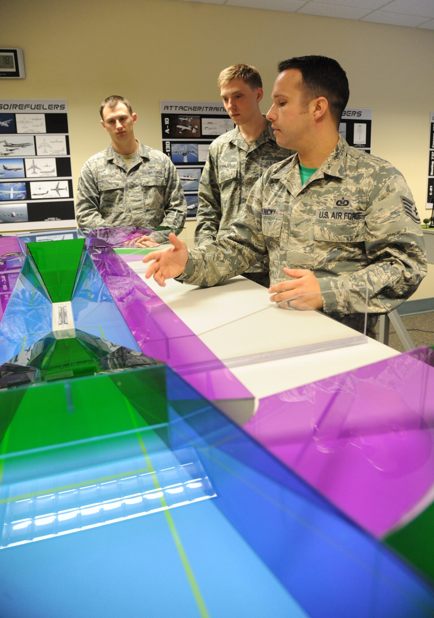 Senior Airmen Ryan Rathke and Marc Stanley, 334th Training Squadron students, listen to Staff Sgt. Courtney Polnicky, 334th TRS airfield management instructor, discuss the training capabilities the new model airfield training aid table offers Dec. 12, 2014, at Cody Hall, Keesler Air Force Base, Miss.  Utilizing the model, which is a scaled representation of an airfield, will increases understanding, productivity and efficiency in the classroom. (U.S. Air Force photo by Kemberly Groue)