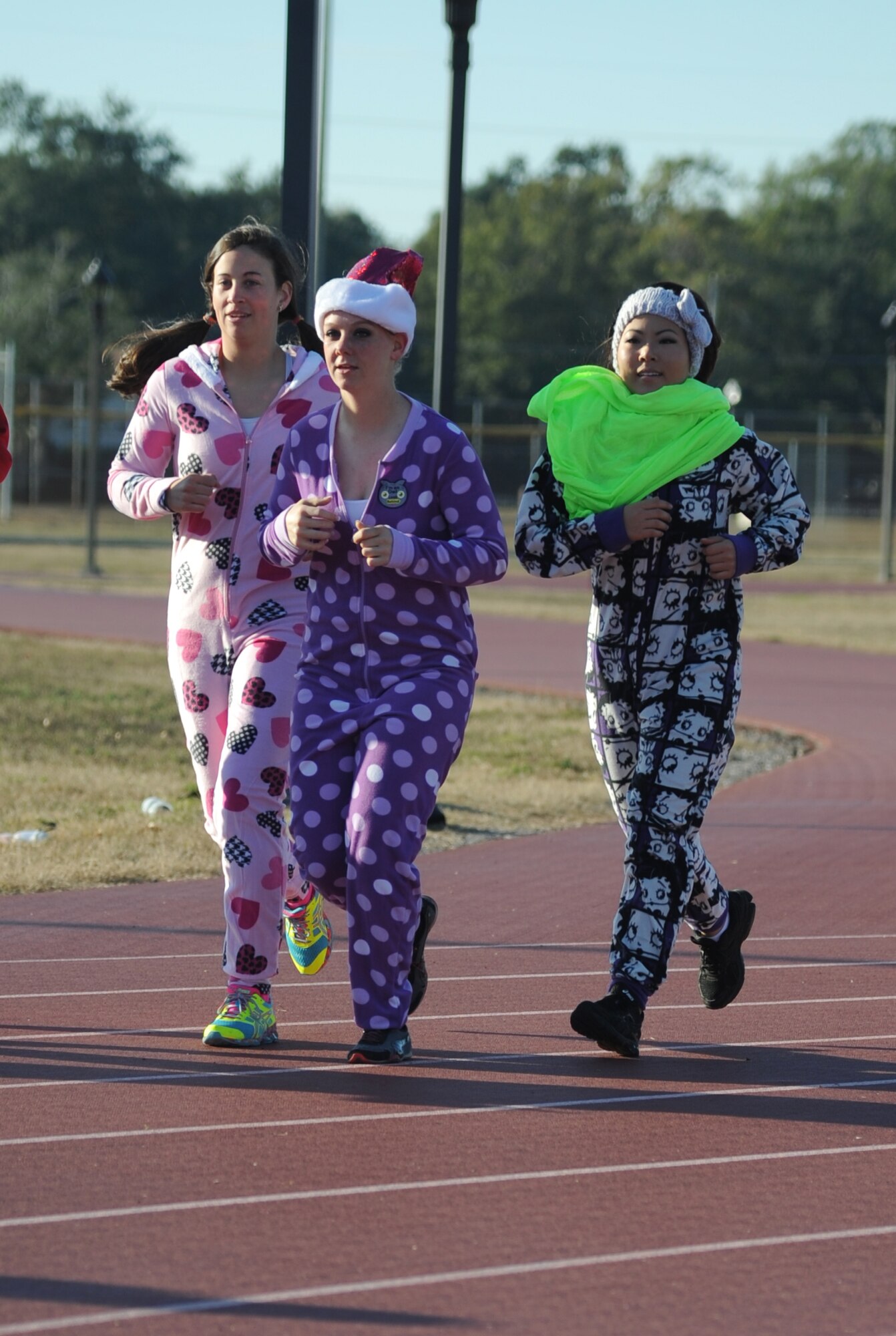 Privates 1st Class Marie-Elana Kennedy and Elise Anderson, and Lance Cpl. Eunice Shim, Keesler Marine Detachment weather students, make a lap around the Triangle Track during a U.S. Marine Corps "Toys for Tots" Foundation fundraising event Dec. 13, 2014, at Keesler Air Force Base, Miss.  Approximately 160 Marines participated in the event, and more than 180 toys were collected for the community outreach event benefiting the Marine Corps "Toys for Tots" campaign. (U.S. Air Force photo by Kemberly Groue)