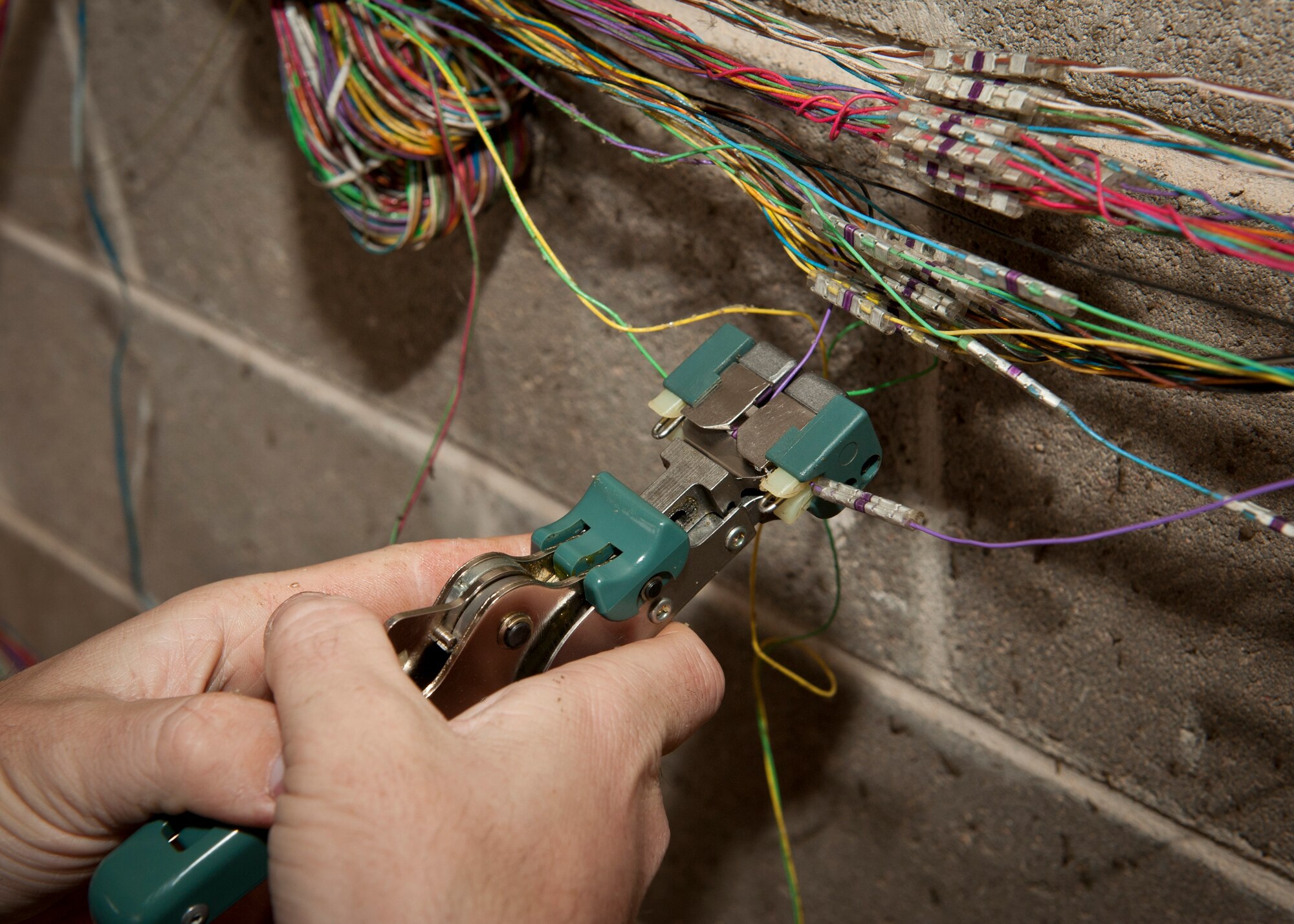 PETERSON AIR FORCE BASE, Colo. – Airman 1st Class Nicholas Ray, 21st Communications Squadron cable and antenna maintenance technician, uses a VS-3 hand tool to splice together wires for training in the cable yard Dec. 8, 2014. The cable and antenna personnel have a training area dedicated to polishing the skills used to keep communications flowing smoothly around base. (U.S. Air Force photo by Airman 1st Class Rose Gudex)