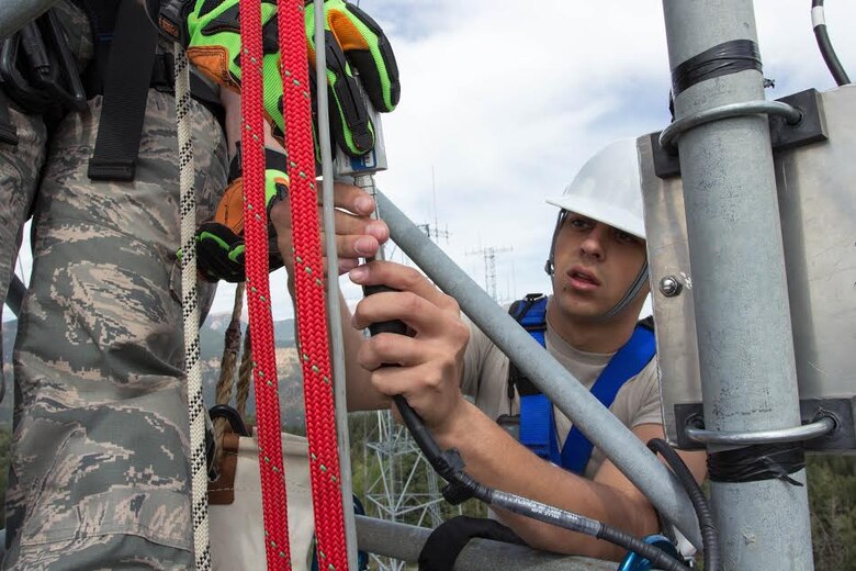 CHEYENNE MOUNTAIN AIR FORCE STATION, Colo. – Senior Airman Dakota Blankenship, 21st Communications Squadron cable and antenna maintenance technician, checks a cable to see if there is power where it should be 100 feet up a tower in July 2014. Those in the cable and antenna maintenance career field often climb towers or work in manholes to make sure connections aren’t causing interference and are working properly. (Courtesy photo)