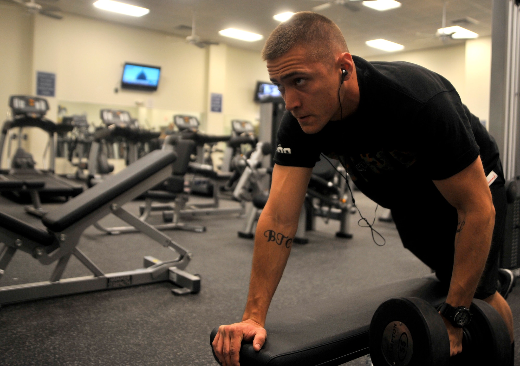 Senior Airman Kyle Honeycutt, 432nd Operations Support Squadron aviation management Airman, performs one-arm dumbbell rows in the Predator Fitness Center Dec. 11, 2014, at Creech Air Force Base, Nevada. The fitness center underwent $172,000 worth of renovations Dec. 4-5, 2014, including new cardio and strength equipment and new flooring. (U.S. Air Force photo by Airman 1st Class Christian Clausen/Released)