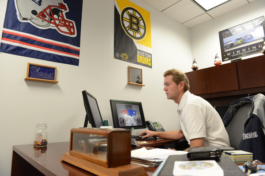 Peter Corbett, 20th Comptroller Squadron unit deployment manager, ensures Airmen have everything they require for deployment at Shaw Air Force Base, S.C., Dec. 16, 2014. Corbett proudly displays paraphernalia of his favorite teams from his home town, Boston, including the Bruins, the Patriots, the Red Sox, and the Celtics to keep moral high and create conversational starters. (U.S. Air Force photo by Airman 1st Class Diana M. Cossaboom/Released)
