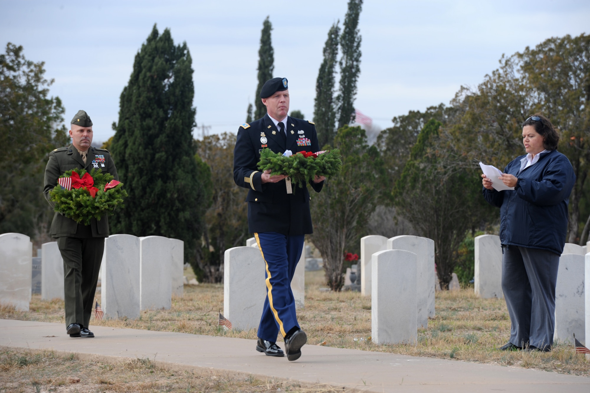 SAN ANGELO, Texas -- Marine Corps Maj. Devin A. Rullman, Goodfellow Air Force Base Marine Corps Detachment Commander, and Army Maj. Scott H. Starr, 344th Military Intelligence Battalion executive officer, carry wreaths to the base of the flagpole at Belvedere Cemetery during the Wreaths Across America ceremony Dec. 13. Wreaths from all services including the Merchant Marines and a Prisoners of War Missing in Action wreath were placed at the flagpole. (U.S. Air Force photo/ Staff Sgt. Laura R. McFarlane)