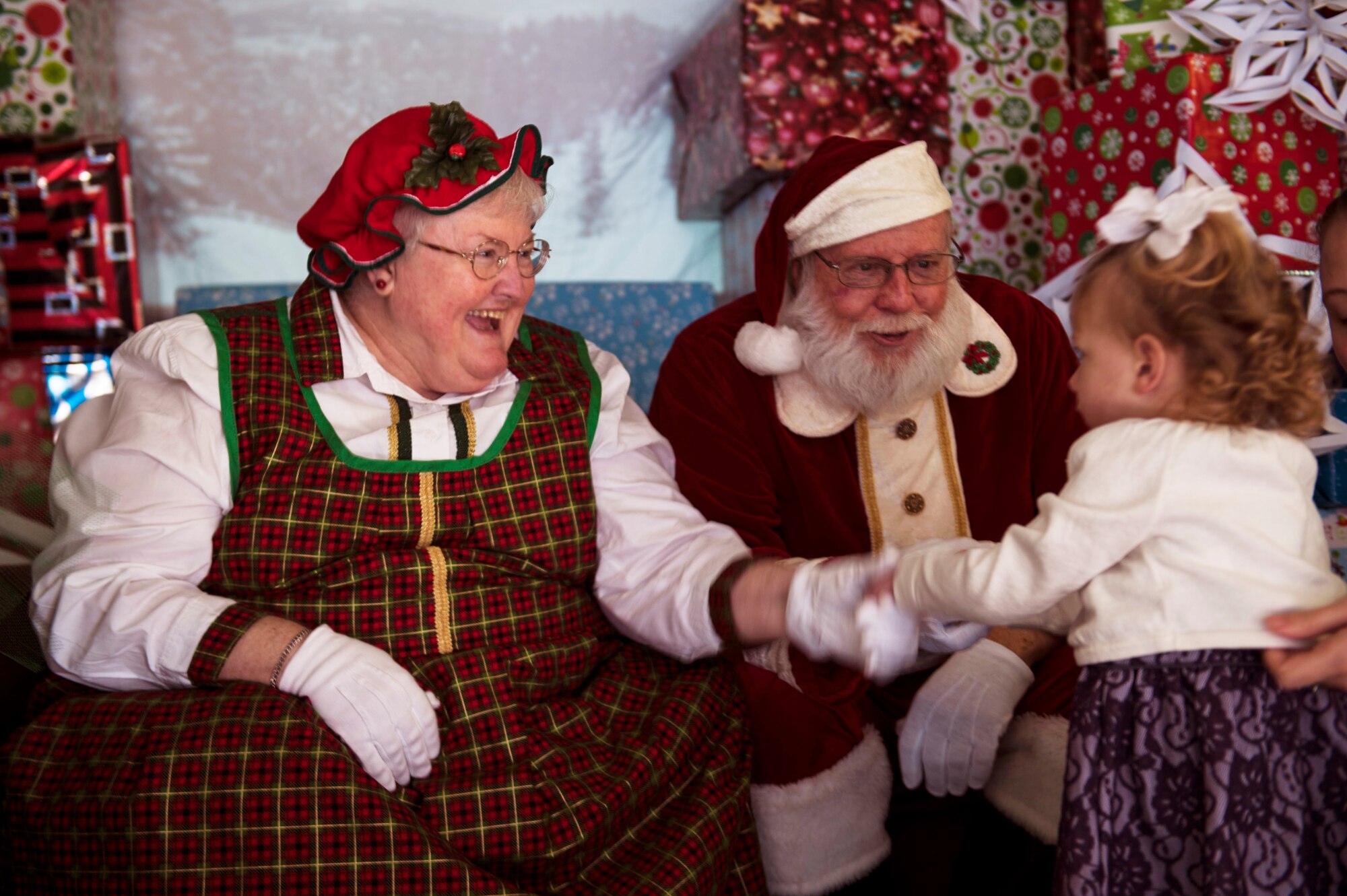 Mrs. Claus shakes hands with Kinlee, daughter of U.S. Air Force Airman 1st Class David Harris, 75th Aircraft Maintenance Unit support technician, during the 23d Maintenance Group and 347th Rescue Group children’s Christmas party Dec. 13, 2014, at Moody Air Force Base, Ga. Afterwards, Kinlee and her father took a family photo with Santa Claus and Mrs. Claus. (U.S. Air Force photo by Airman 1st Class Dillian Bamman/Released)